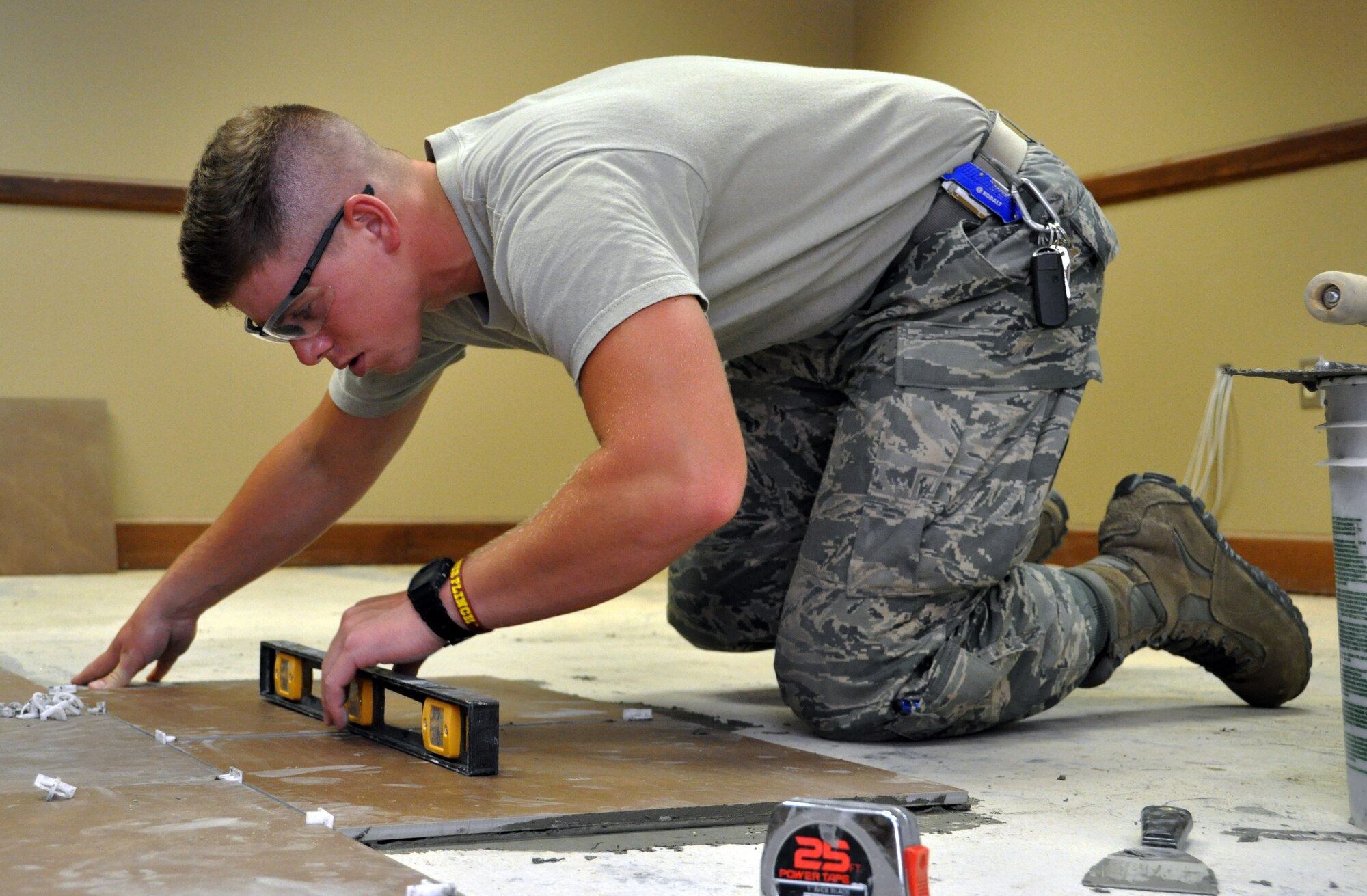 Senior Airman Robert James, 931st Civil Engineer Squadron, uses a bubble level to ensure a newly installed floor tile is level in Building 1218 at McConnell Air Force Base, Kan., July 11, 2014.  James and several other members of the 931 CES spent the July Unit Training Assembly installing new floor tiles in the building as part of a renovation project conducted by Civil Engineer Airmen from both the active-duty 22nd Air Refueling Wing and the Air Force Reserve 931st Air Refueling Group.  ).  931 CES Airmen consistently work together with their active duty counterparts from the 22nd Air Refueling Wing to repair and improve the facilities of McConnell Air Force Base.  (U.S. Air Force photos by Capt. Zach Anderson)