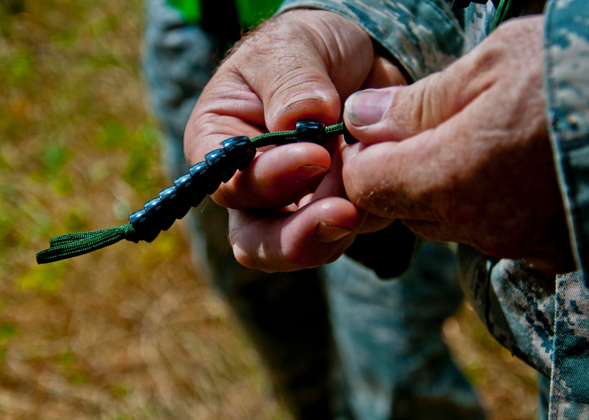 A medic from the 446th Aeromedical Staging Squadron uses ranger beads to estimate distance travelled for land navigation training during the Care Under Fire exercise at Joint Base Lewis-McChord, July 12, 2015.  The Care Under Fire exercise was designed locally by the 446th ASTS in order to simulate combat conditions and establish team oriented training scenarios. Medics were offered land navigation training in order to enhance their combat readiness in austere locations. (U.S. Air Force photo by Senior Airman Daniel Liddicoet/Released)