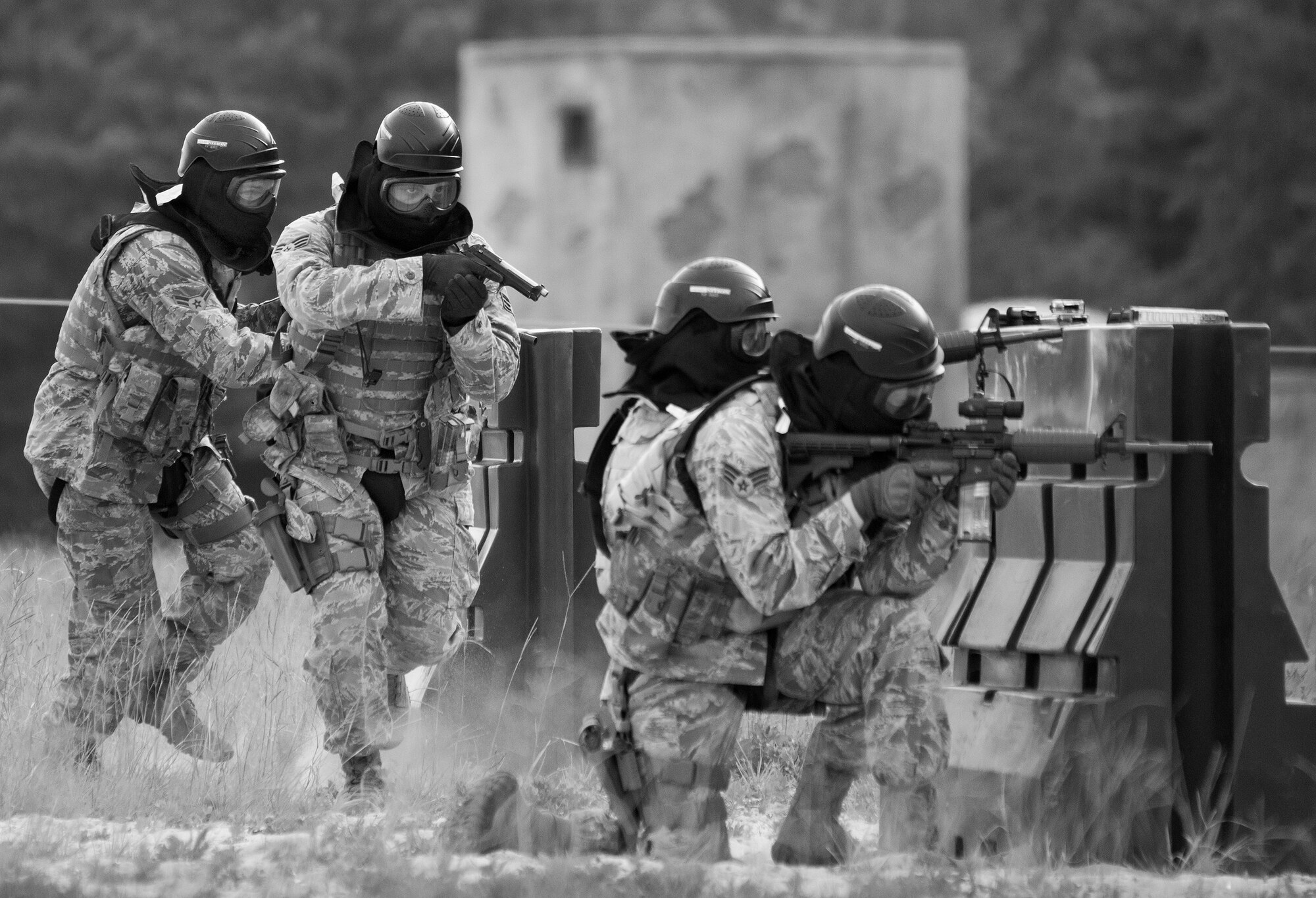 A team of 96th Security Forces Squadron Airmen perform a side-advancing movement during a shoot, move and communicate drill in June at Eglin Air Force Base, Fla.  This mandatory training requirement is in addition to the Airmen's annual weapons qualification training.  The exercise consists of Airmen firing simmunition ammo while advancing toward, away from and to the side of a target.  This is followed by a building sweep and clear drill. Eglin’s security forces personnel protect and defend the main base, facilities, gates, Duke Field, 7th SFG compound and land and water ranges.  (U.S. Air Force photo/Tech. Sgt. Sam King)