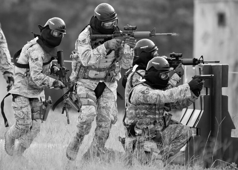 A team of 96th Security Forces Squadron Airmen perform a side-advancing movement during a shoot, move and communicate drill in June at Eglin Air Force Base, Fla.  The mandatory training requirement is in addition to annual weapons qualification training.  The exercise consists of Airmen firing simmunition ammo while advancing toward, away from and to the side of a target.  This is followed by a building sweep and clear drill. Eglin’s security forces personnel protect and defend the main base, facilities, gates, Duke Field, 7th SFG compound and land and water ranges.  (U.S. Air Force photo/Tech. Sgt. Sam King)