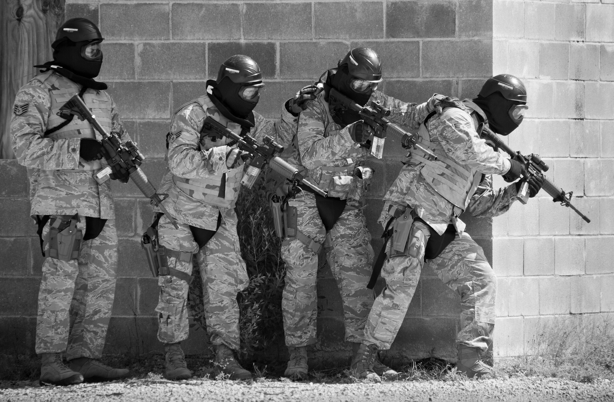 A team of 96th Security Forces Squadron Airmen prepare to enter a building during a shoot, move and communicate drill in June at Eglin Air Force Base, Fla.  The mandatory training requirement is in addition to annual weapons qualification training.  The exercise consists of Airmen firing simmunition ammo while advancing toward, away from and to the side of a target.  This is followed by a building sweep and clear drill.  Eglin’s security forces personnel protect and defend the main base, facilities, gates, Duke Field, 7th SFG compound and land and water ranges.  (U.S. Air Force photo/Tech. Sgt. Sam King)