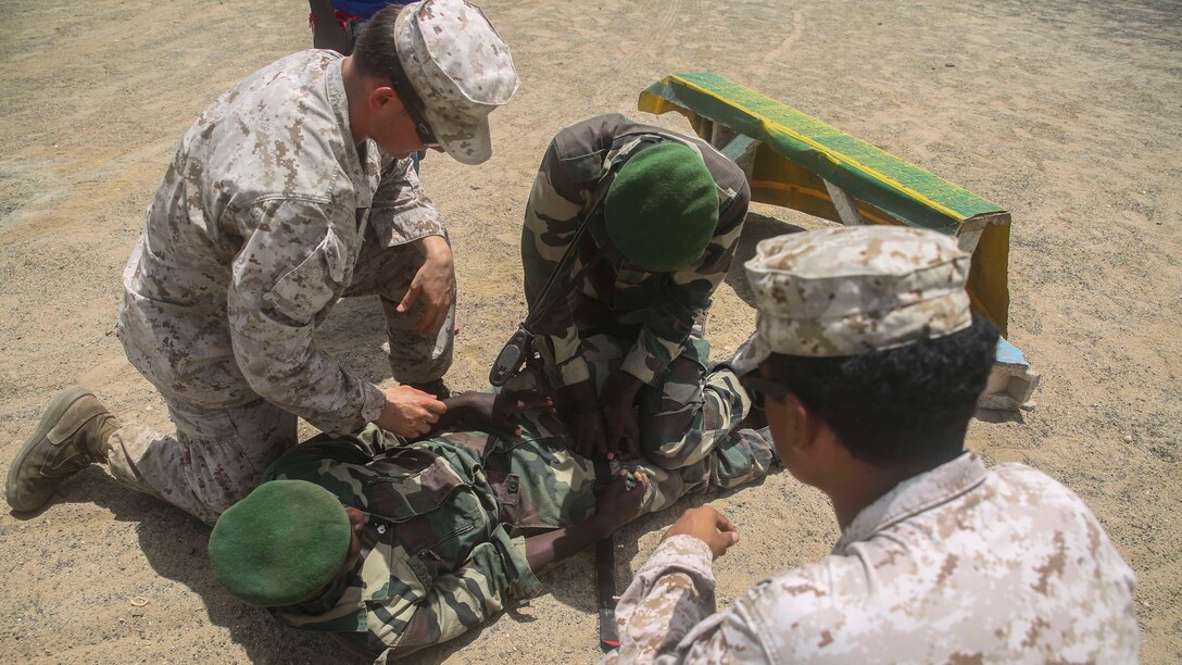 U.S. Marine Cpl. Jacob Jones, left, and U.S. Navy Petty Officer 3rd Class Brandon Vides, right, observe as a member of the Senegalese Compagnie Fusilier de Marin Commandos  applies a tourniquet to a simulated casualty during a skills competition in St. Louis, Senegal, July 2, 2015. Jones is an assistant infantry skills instructor and Vides is a hospitalman assigned to Special-Purpose Marine Air-Ground Task Force Crisis Response-Africa. More than 15 U.S. Marines and Sailors with the unit held a weapons and combat medical skills competition for more than 30 members of the Fusilier Marins in an effort to build and sustain infantry fundamentals. 