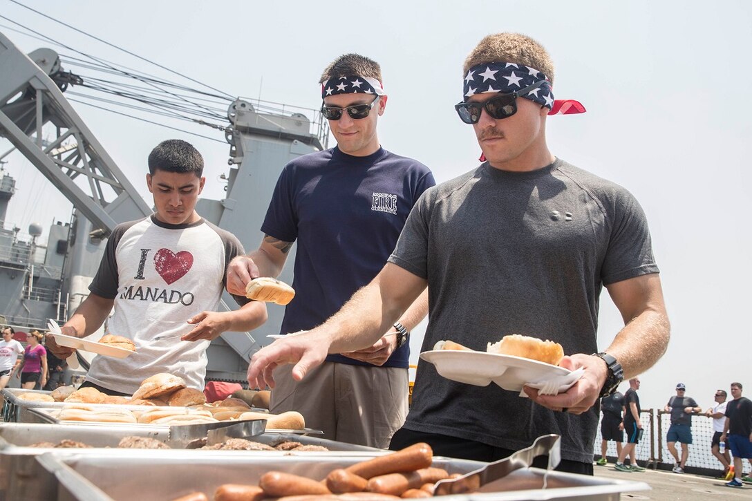 ARABIAN GULF (July 4, 2015) U.S. Marines and Sailors with the 15th Marine Expeditionary Unit and Essex Amphibious Group fix themselves a plate of food during a steel beach in observance of Independence Day aboard the dock landing ship USS Rushmore (LSD 47). Marines with Combat Logistics Battalion 15, 15th MEU, celebrated with the reading of the Declaration of Independence and with an American style barbeque on the flight deck. The 15th MEU is embarked on the Essex ARG and deployed to maintain regional security in the U.S. 5th Fleet area of operations. (U.S. Marine Corps photo by Sgt. Emmanuel Ramos/Released)