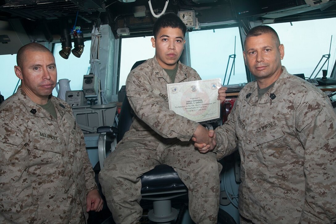 GULF OF ADEN (July 10, 2015) U.S. Marine Sgt. Maj. Jorge Melendez, left, and Sgt. Maj. Douglas Schaefer, right, congratulate the 15th Marine Expeditionary Unit’s “Marine of the Week” awardee Lance Cpl. Miguel  A. Garces aboard the amphibious assault ship USS Essex (LHD 2). Melendez is the sergeant major of Battalion Landing Team 3rd Battalion, 1st Marine Regiment, 15th MEU and Schaefer is the sergeant major of the 15th MEU. Garces is from Mercedes, Texas, and is a field artillery cannoneer with India Battery, BLT 3/1.  Garces provided a myriad of classes during the week that range from machine gun characteristics and employment to artillery operations. He has been instrumental in the serviceability of $2.5 million worth of gear and equipment for his section through preventative maintenance checks. Garces has proven his dedication to the progress and training of the Marines through his countless hours of instruction, guidance, and hard work. He has been filling in as the section chief in the absence of his noncommissioned officer but has the full confidence and faith of his entire chain of command and operates in the capacity of an NCO on a daily basis. The 15th MEU is embarked on the Essex Amphibious Ready Group and deployed to maintain regional security in the U.S. 5th Fleet area of operations. (U.S. Marine Corps photo by Staff Sgt. Miguel Carrasco/Released)