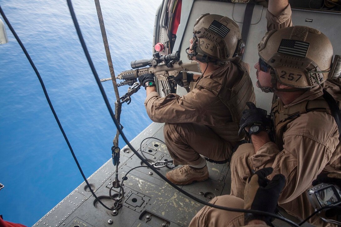 GULF OF ADEN (July 7, 2015) U.S. Marines with the 15th Marine Expeditionary Unit’s Maritime Raid Force look for their targets from an MH-60S Sea Hawk from the “Blackjacks” of Helicopter Sea Combat Squadron 21. These Marines practiced aerial sniping out of the helicopter to work on their accuracy shooting from the air. The 15th MEU is embarked on the Essex Amphibious Ready Group and deployed to maintain regional security in the U.S. 5th Fleet area of operations. (U.S. Marine Corps photo by Cpl. Anna Albrecht/Released)