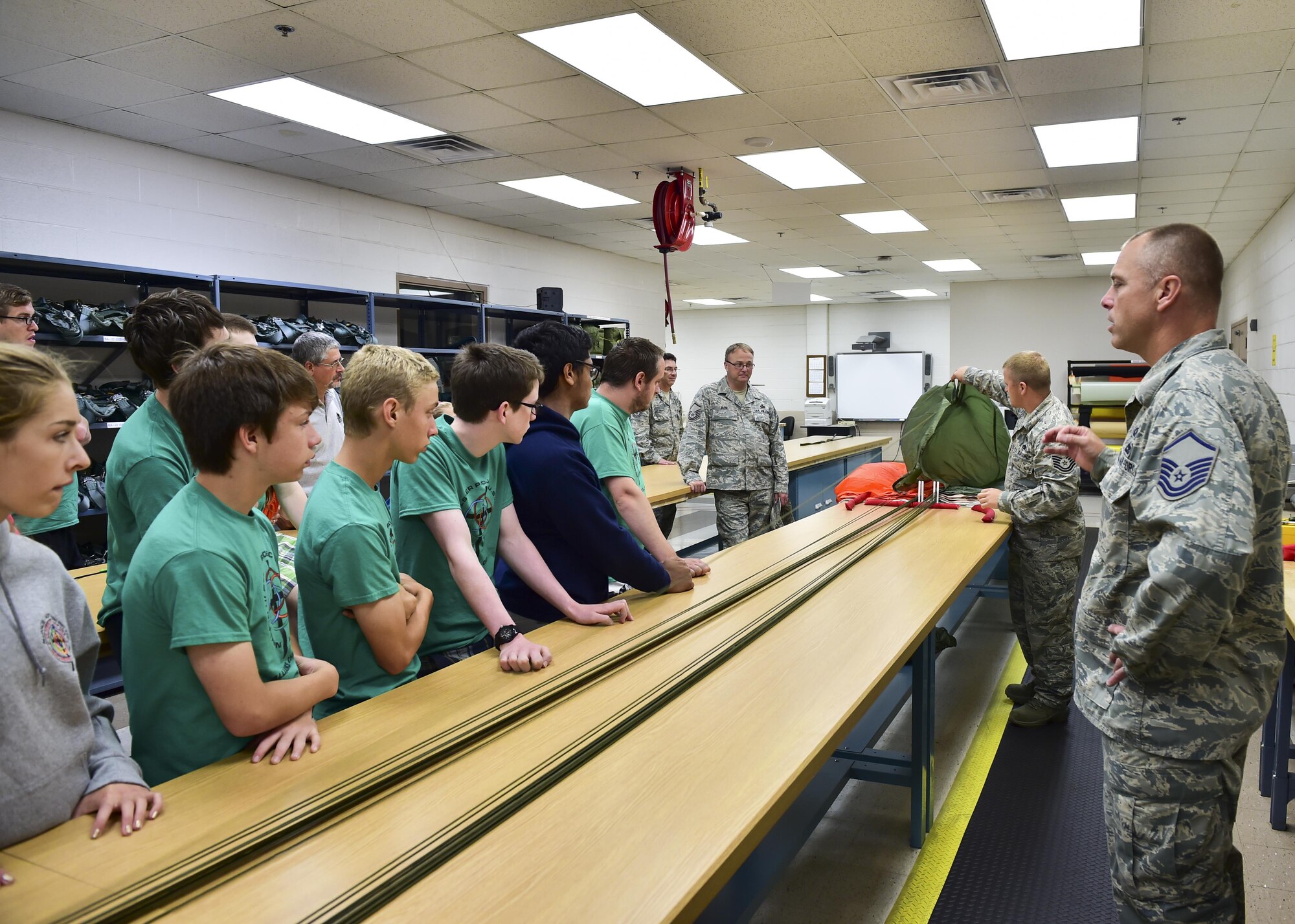 Master Sgt. Don McCormick, (front) superintendent of life support equipment with the 910th Maintenance Squadron, and Tech. Sgt. Ed Pegg, aircrew flight equipment crafstman, demonstrate how they inspect paracute canopies for defects or damage during a tour here, July 10, 2015. The Alliance Ulster Project, which exists to promote unity between Roman Catholics and Protestants, brought a group of U.S. and Irish teenagers to tour Youngstown Air Reserve Station as part of their summer program. U.S. Air Force photo/Eric M. White