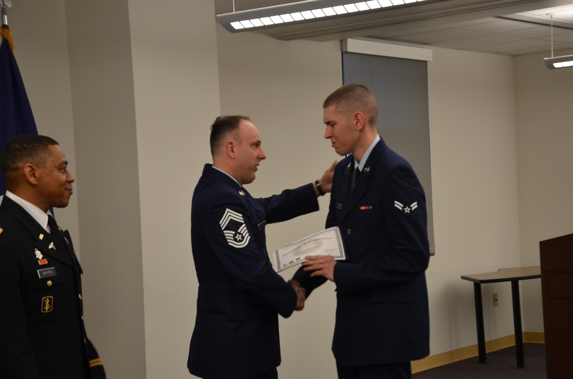 Chief Master Sgt. Charles Frizzell presents his son, Airman Christian Frizzell, with his graduation certificate during his Biomedical Equipment Technician class graduation ceremony April 10 at the Medical Education and Training Campus. Airman Frizzell is starting his new career at Wright-Patterson Air Force Base, Ohio. His father, also a BMET, is currently assigned as the senior enlisted advisor to the commander at the 374th Medical Group at Yokota Air Base, Japan. (Photo by Lisa Braun) 