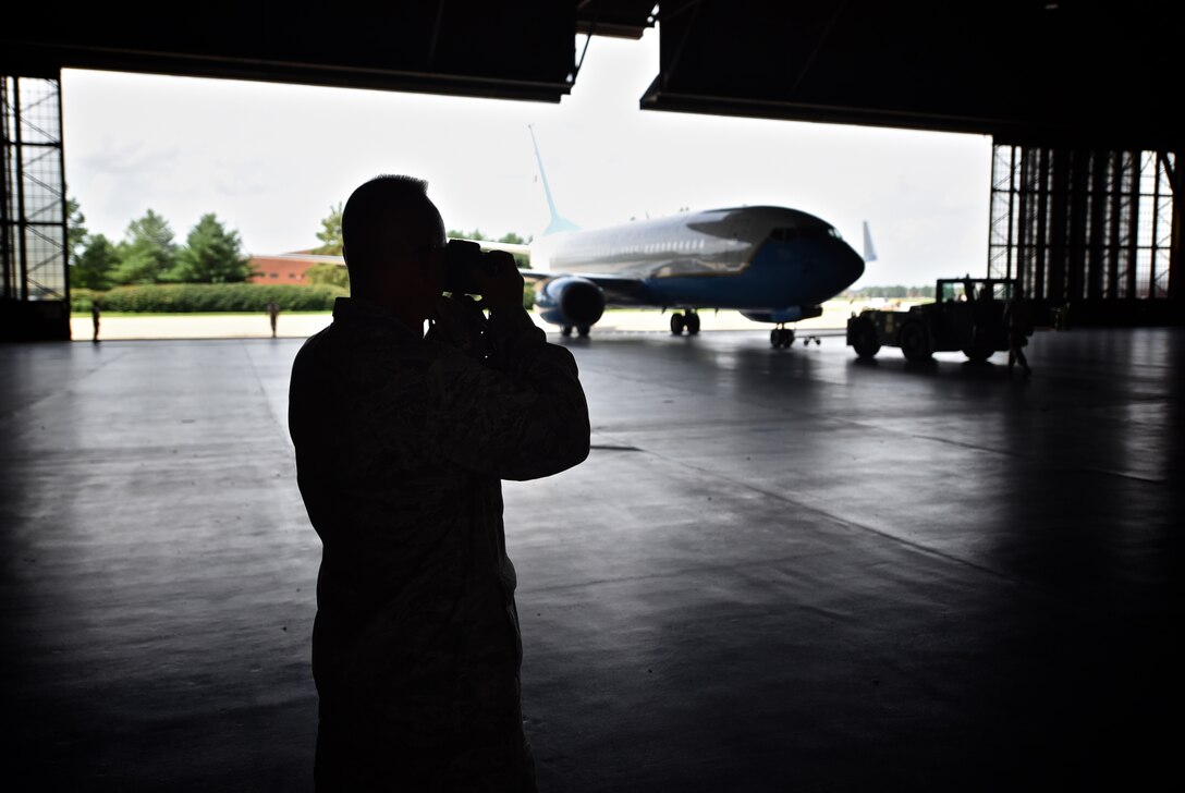 Maj. Stan Paregien, the 932nd Airlift Wing Public Affairs officer, is silhouetted while capturing a quick photo inside Hanger 1 as a 932nd AW C-40 is brought in for maintenance at Scott Air Force Base Ill., July 11, 2015. (U.S. Air Force photo by Tech. Sgt. Christopher Parr)