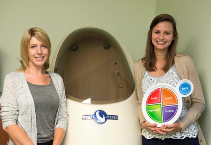 Nikki Conley, Health Promotion program manager (left)) and Alaine Mills, Health Promotion nutrition program manager, pose for a photo in front of a Bod Pod, a unit designed to measure a person’s body fat percentage, June 17, 2015, at Joint Base Charleston, S.C. Health Promotion, formally known as the Health and Wellness Center or HAWC, has recently changed its name and focus from a wellness center focusing on individual health, to a base-wide program focusing on overall base fitness. (U.S. Air Force photo/Senior Airman Jared Trimarchi) 