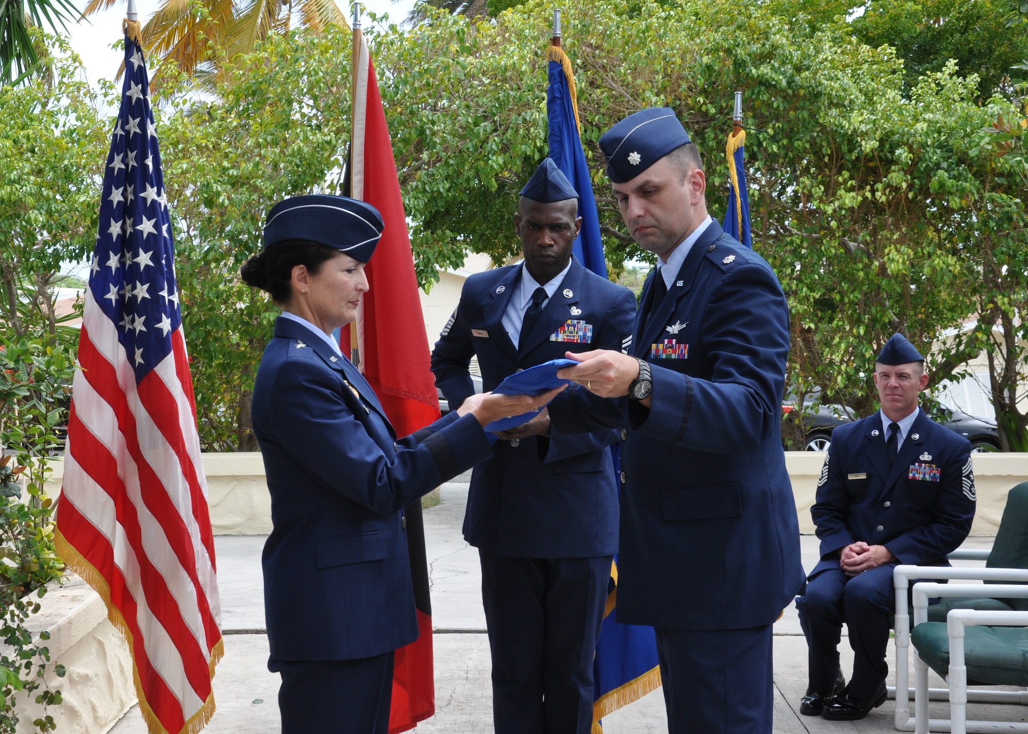 Brig. Gen. Nina Armagno, 45th Space Wing commander and presiding officer, cases the Detachment 1 guidon in a sleeve with assistance from Lt. Col. Steven Melvin, Det 1, 45th Operations Group commander, while Senior Master Sgt. Kwame Tawiah, Det 1, 45th OG superintendent, center, holds the guidon steady and Chief Master Sgt. Craig Neri, 45th SW command chief, back, observes during the deactivation ceremony of Antigua Air Station July 7, 2015, in Antigua. Rolling and casing the detachment colors in a sleeve symbolizes the organizations inactive status. (U.S. Air Force photo by 1st Lt. Alicia Wallace)(Released)