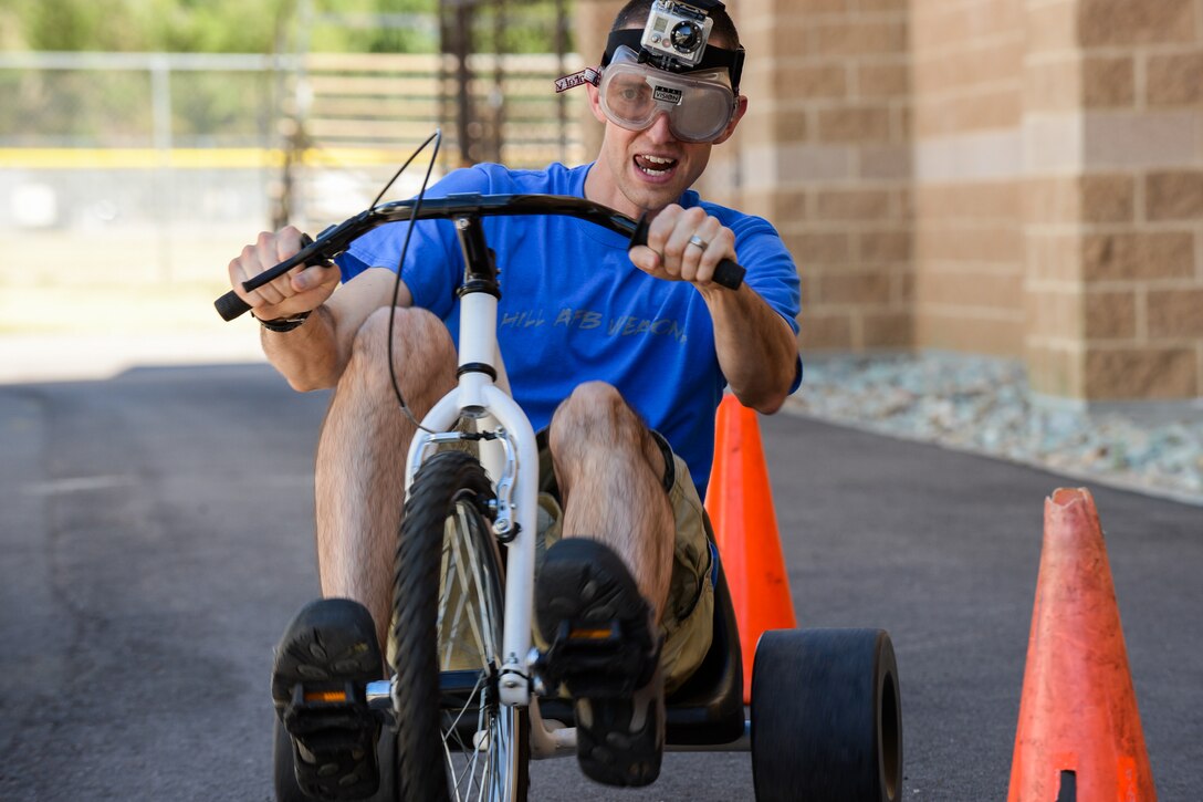 Staff Sgt. Travis Brown, 388th Maintenance Group,  rides a tricycle through a cone obstacle while wearing impairment goggles during an Airmen Against Drunk Driving awareness event held at the Warrior Fitness Center June 26. (R. NIAL BRADSHAW/U.S. Air Force)