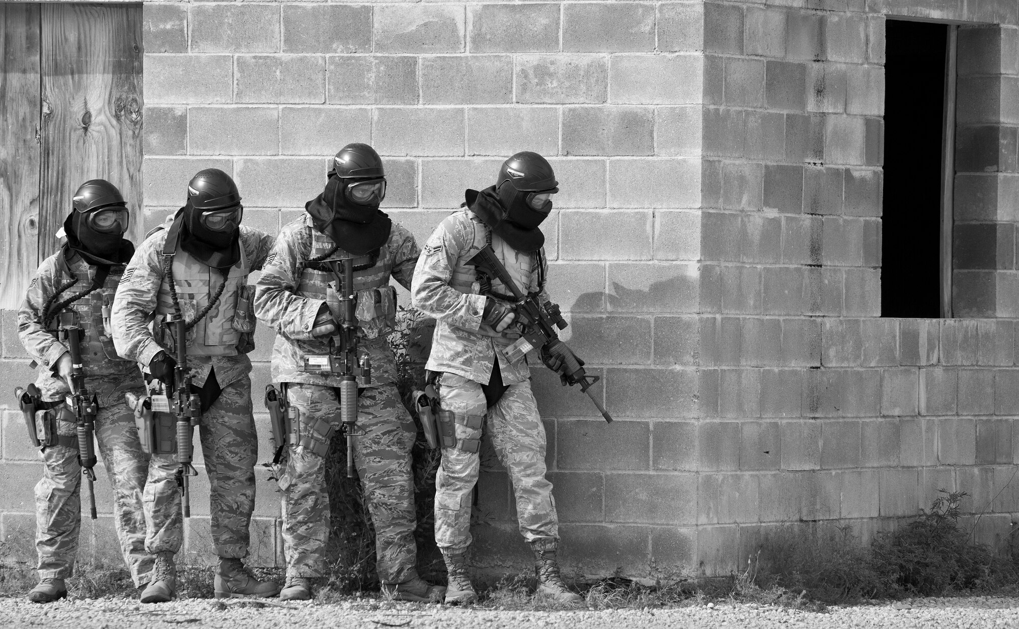 A team of 96th Security Forces Squadron Airmen prepare to enter a building during a shoot, move and communicate drill in June at Eglin Air Force Base, Fla.  The mandatory training requirement is in addition to annual weapons qualification training.  The exercise consists of Airmen firing simmunition ammo while advancing toward, away from and to the side of a target.  This is followed by a building sweep and clear drill.  The Defenders perform the highly kinetic training at Eglin’s Base Tango range.  The range was previously used for security forces pre-deployment training.  (U.S. Air Force photo/Samuel King Jr.)