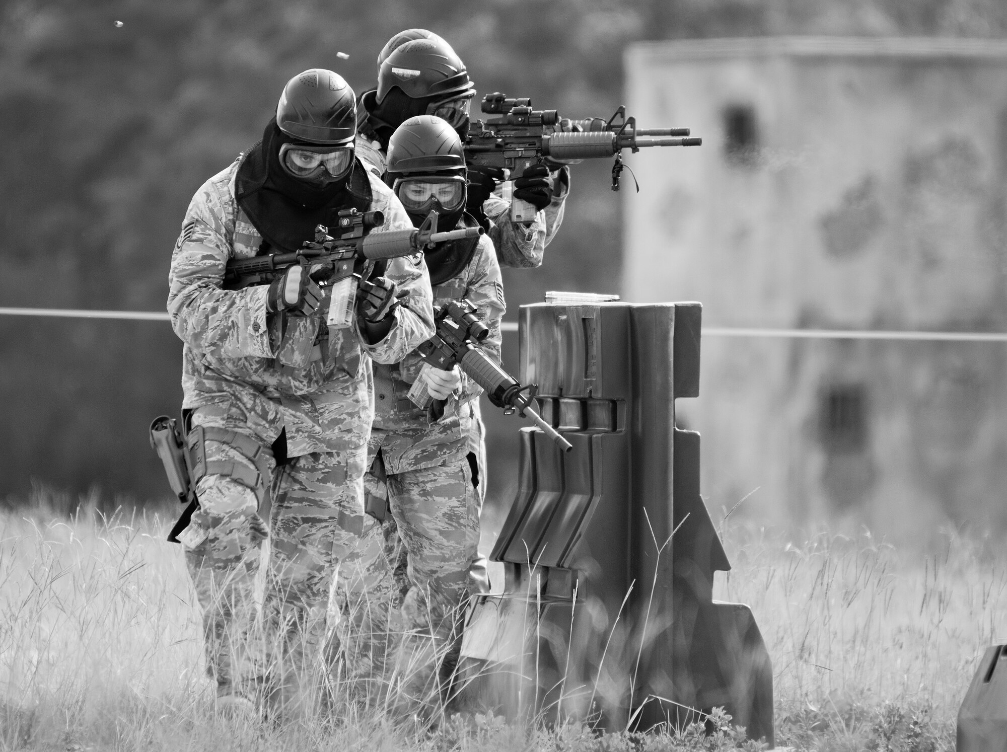 A team of 96th Security Forces Squadron Airmen perform a side-advancing movement during a shoot, move and communicate drill in June at Eglin Air Force Base, Fla.  The mandatory training requirement is in addition to annual weapons qualification training.  The exercise consists of Airmen firing simmunition ammo while advancing toward, away from and to the side of a target.  This is followed by a building sweep and clear drill.  The Defenders perform the highly kinetic training at Eglin’s Base Tango range.  The range was previously used for security forces pre-deployment training.  (U.S. Air Force photo/Samuel King Jr.)