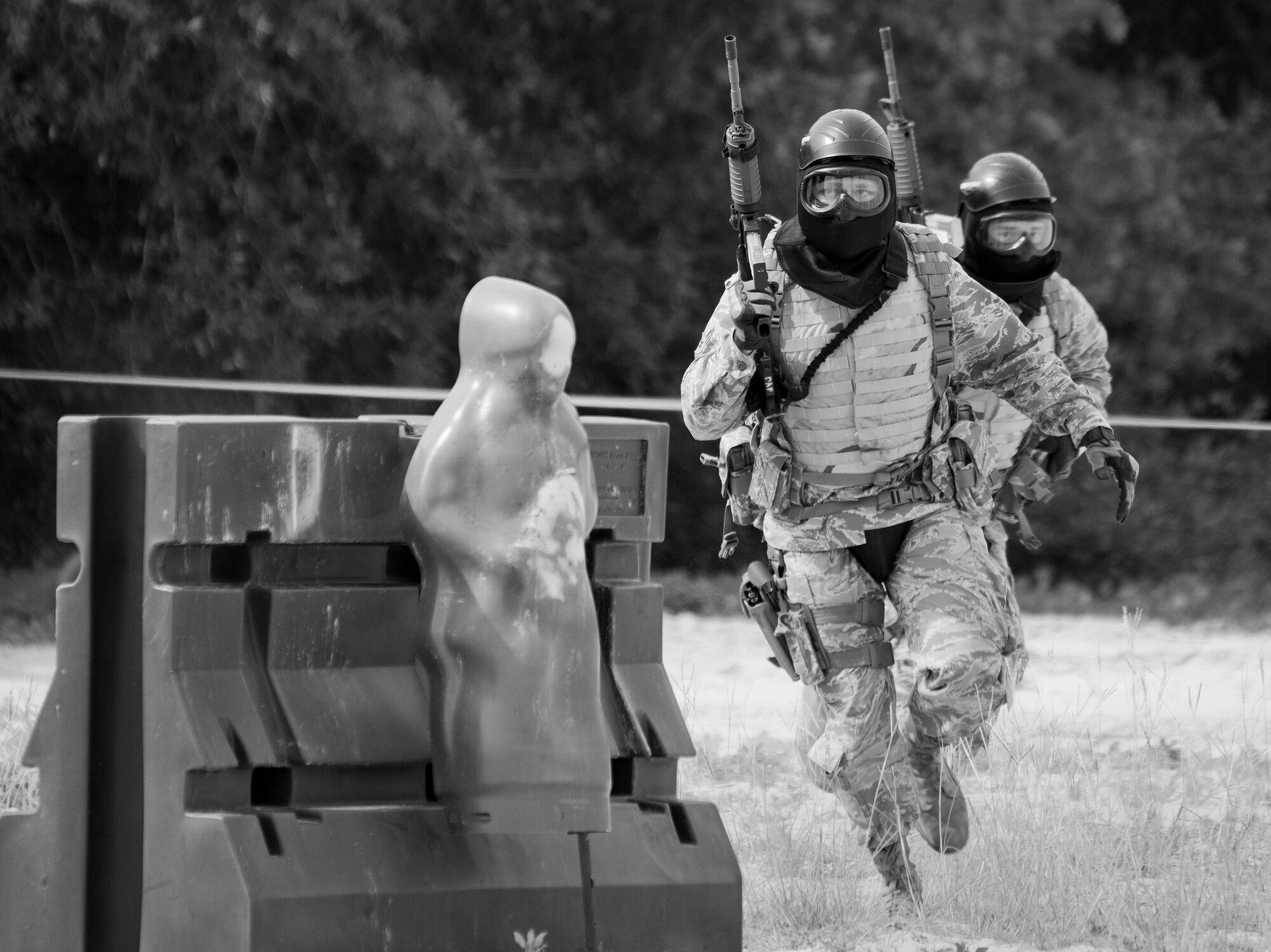 A two-person team of 96th Security Forces Squadron Airmen move toward a barrier during a shoot, move and communicate drill in June at Eglin Air Force Base, Fla.  The mandatory training requirement is in addition to annual weapons qualification training.  The exercise consists of Airmen firing simmunition ammo while advancing toward, away from and to the side of a target.  This is followed by a building sweep and clear drill.  The Defenders perform the highly kinetic training at Eglin’s Base Tango range.  The range was previously used for security forces pre-deployment training.  (U.S. Air Force photo/Samuel King Jr.)