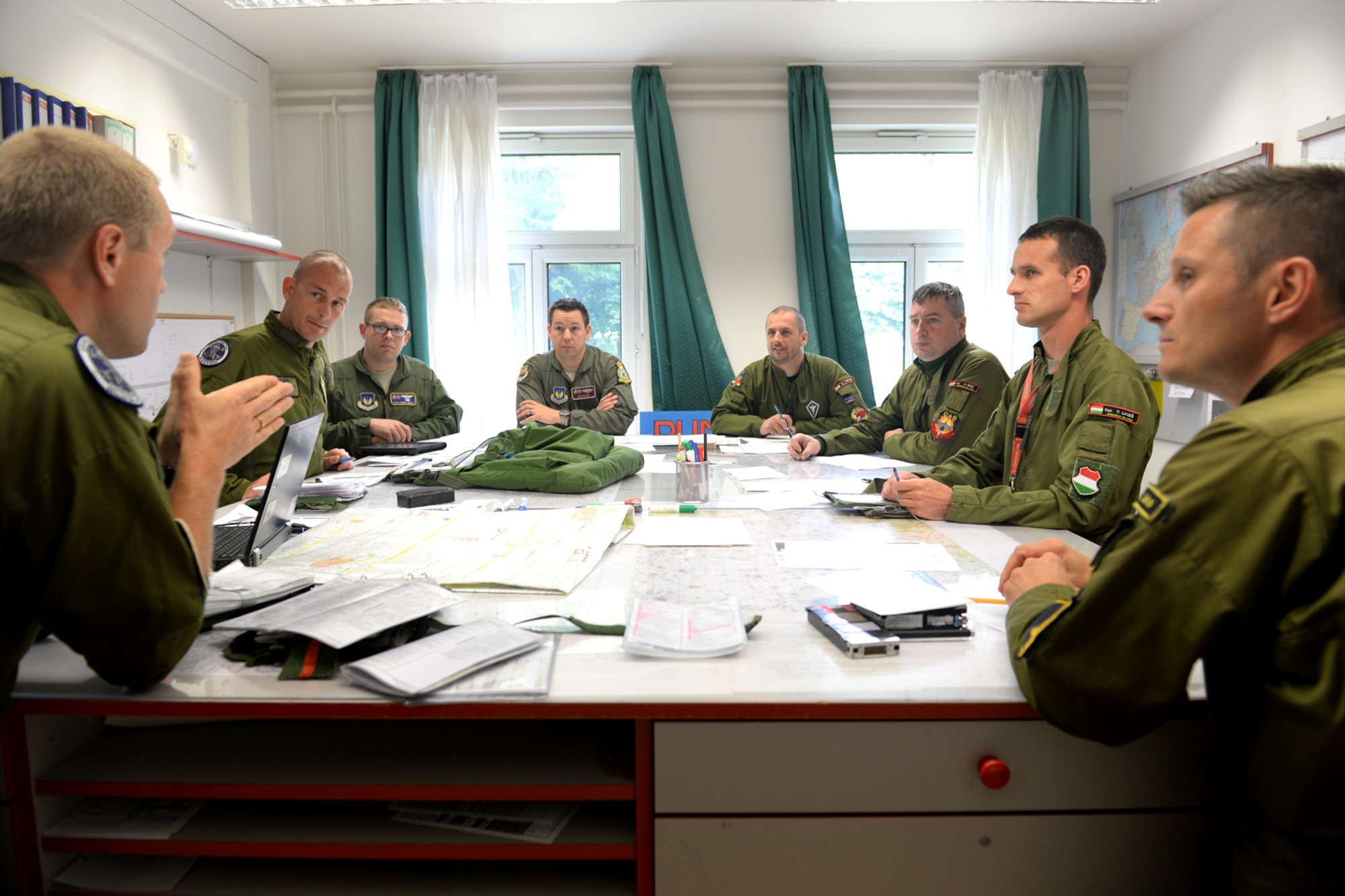 Swedish air force Capt. Fredrik Borgsrtöm, Swedish AF Gripen Operational Testing and Evaluation instructor pilot, discusses the flight plan with U.S. and Hungarian air forces prior to flying June 24, 2015, during AR familiarization training on Kecskemét air base, Hungary. The familiarization started with two days of classroom academics then each Hungarian Gripen pilot flew with a Swedish instructor pilot for hands-on practice. (U.S. Air Force photo by Senior Airman Kate Thornton/Released)