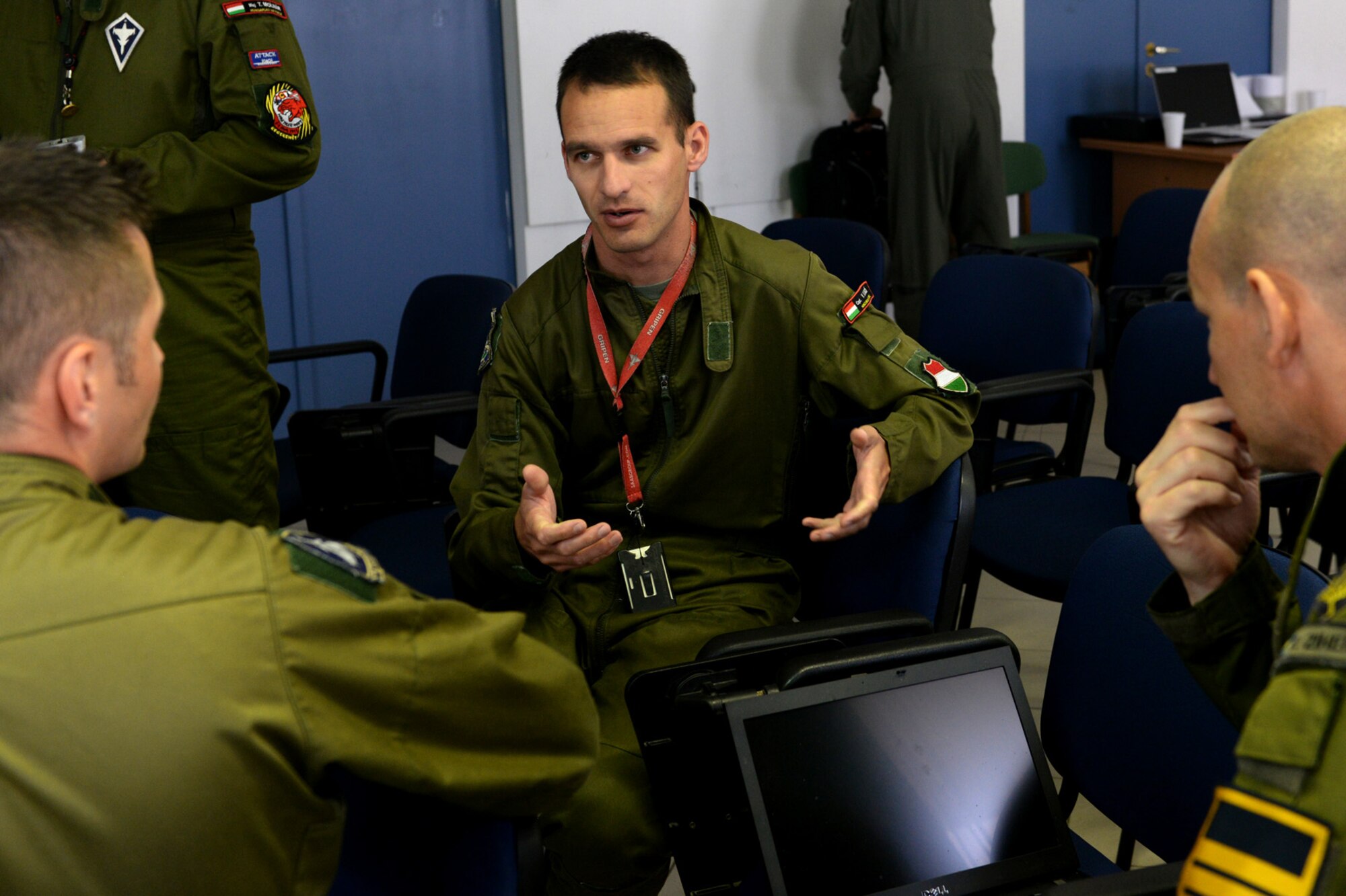 A Hungarian air force JAS-39 Gripen pilot discusses air refueling with Swedish air force Lt. Col. Pierre Ziherl and Maj. Henrik Lahti, Swedish AF Gripen Operational Testing and Evaluation instructor pilots, before their flight June 24, 2015, during AR familiarization training on Kecskemét air base, Hungary. The familiarization started with two days of classroom academics then each Hungarian Gripen pilot flew with a Swedish instructor pilot for hands-on practice. (U.S. Air Force photo by Senior Airman Kate Thornton/Released)