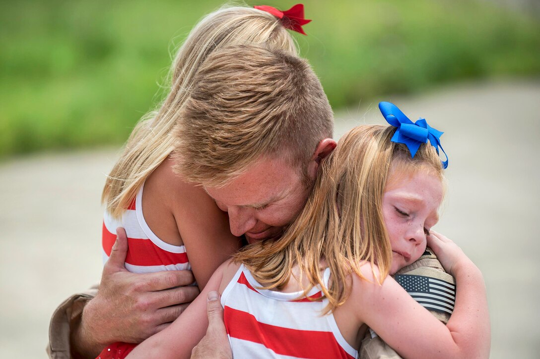 U.S. Air Force Capt. Ross Farling hugs his daughters during a homecoming ceremony at the Kentucky Air National Guard Base in Louisville, Ky., July 4, 2015. Farling was among 39 guardsmen who returned from a deployment to the Persian Gulf region, where they supported Operation Freedom's Sentinel. Farling is a C-130 Hercules pilot assigned to the 123rd Airlift Wing.