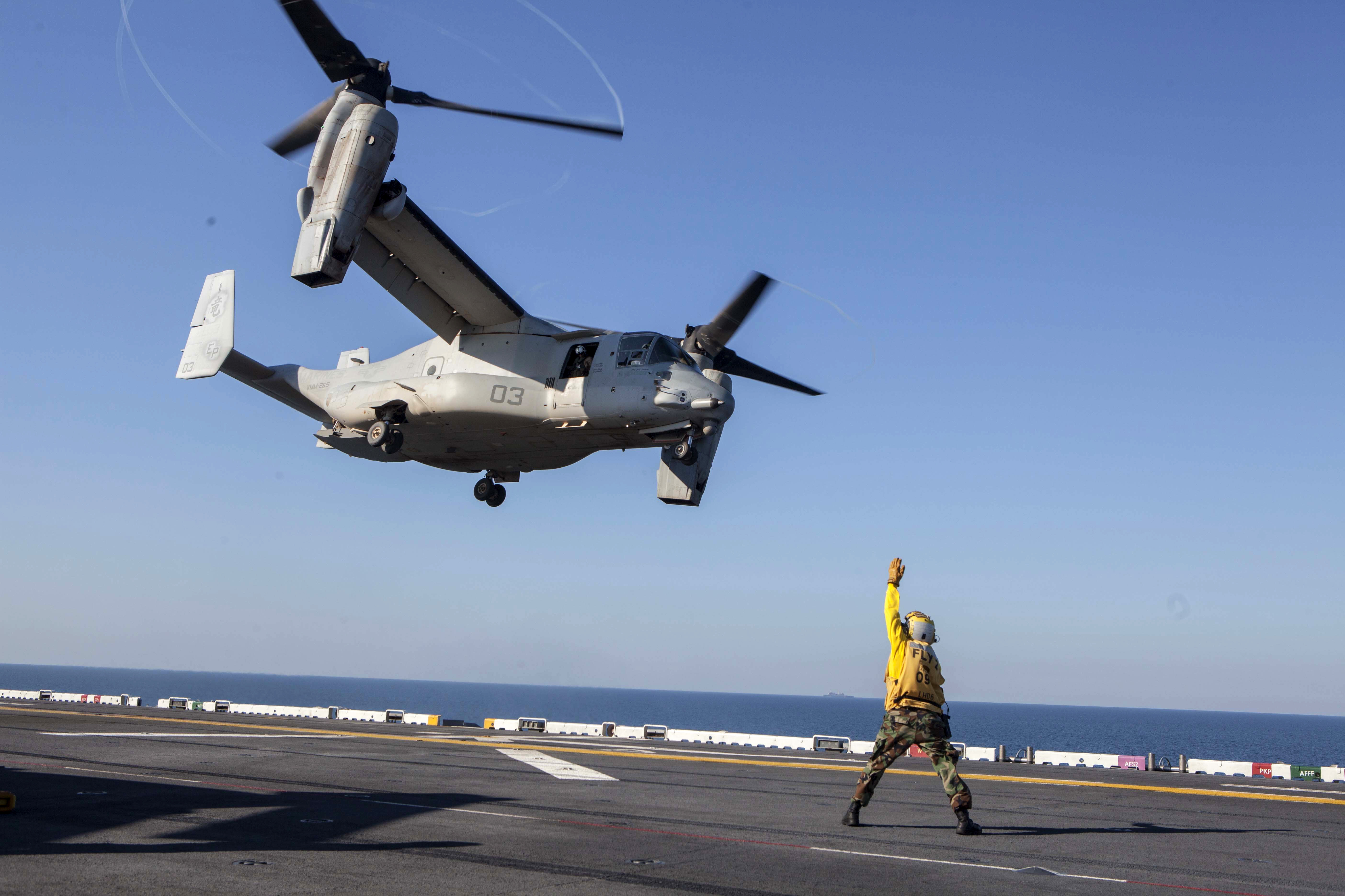 A U.S. sailor gives the takeoff signal to an MV-22 Osprey during ...