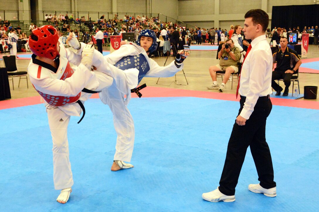 Army 1st Lt. Joshua Fletcher, center, attempts to score a head kick to ...