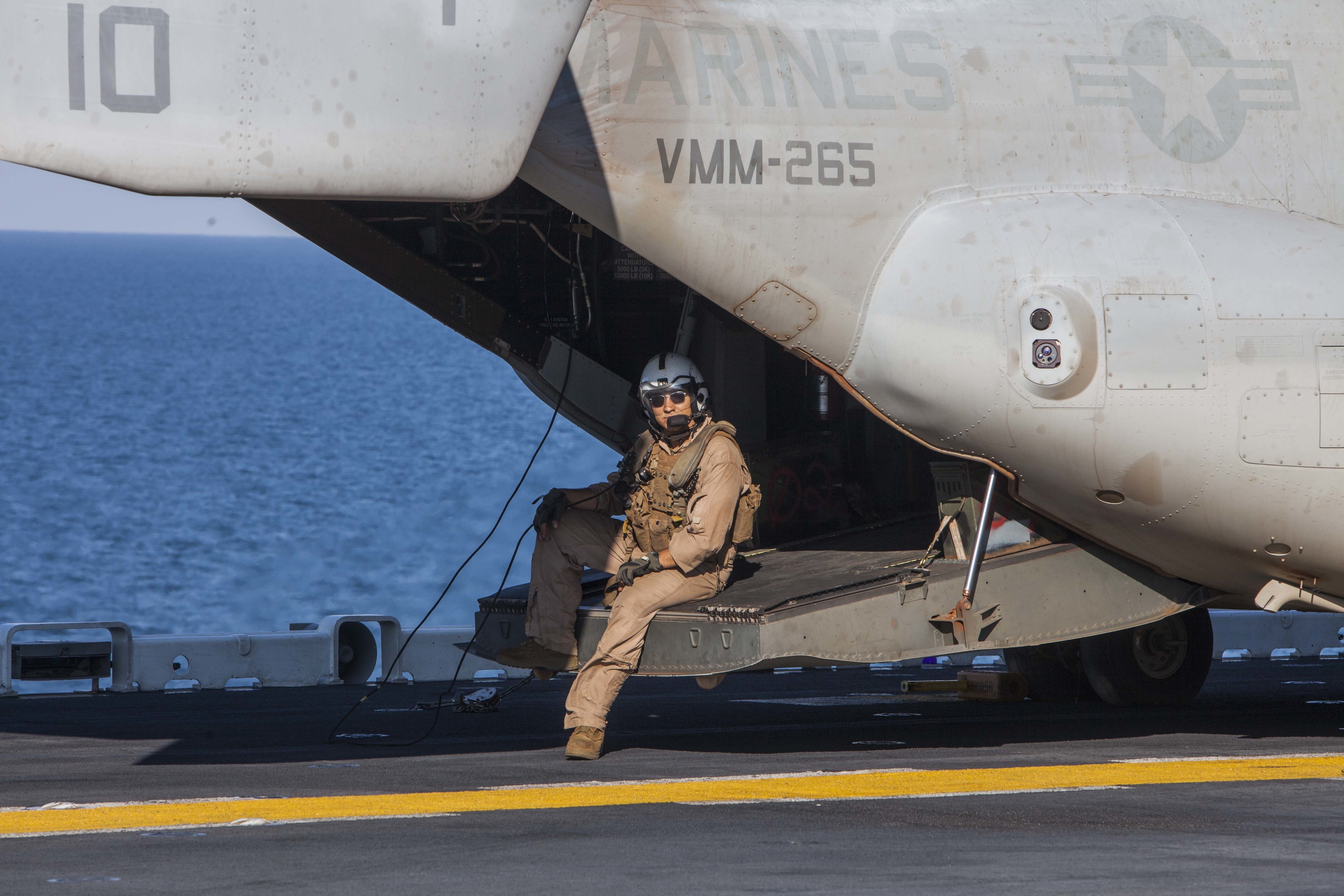 A U S Marine waits as an MV 22 Osprey is refueled during exercise