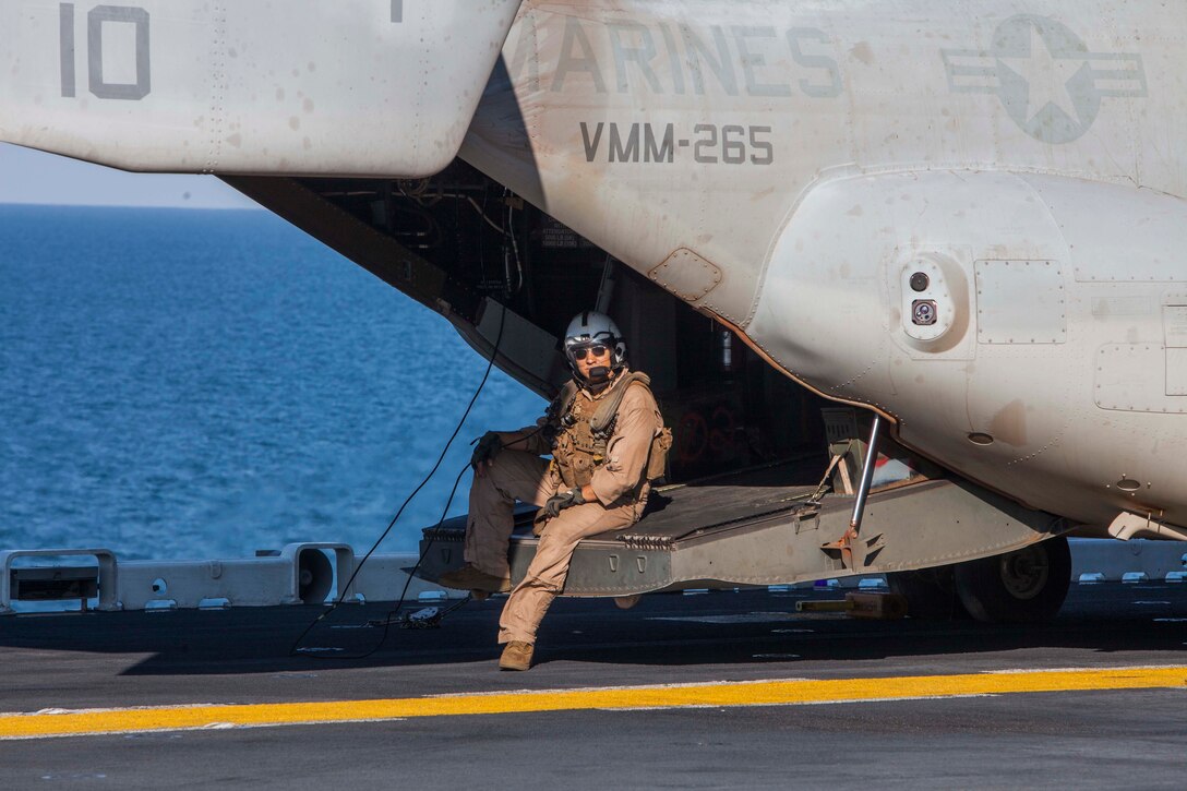 A U.S. Marine waits as an MV-22 Osprey is refueled during exercise Talisman Sabre 2015 aboard the USS Bonhomme Richard at sea near Australia, July 11, 2015. The Marine is a crew chief.