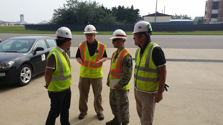 Chris Martin, (2nd from left) discusses quality control issues with contractors outside a job site on Kunsan Air Base.