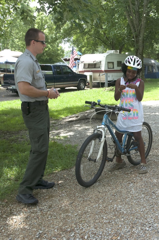 Park Ranger Phillip Sliger rewards Jordan Johnson with a voucher for a McDonalds treat July 9, 2015 for wearing her helmet while riding her bike at Defeated Creek Campground in Defeated, Tenn., on the shore of Cordell Hull Lake. Jordan was camping with her mother Melissa Johnson.