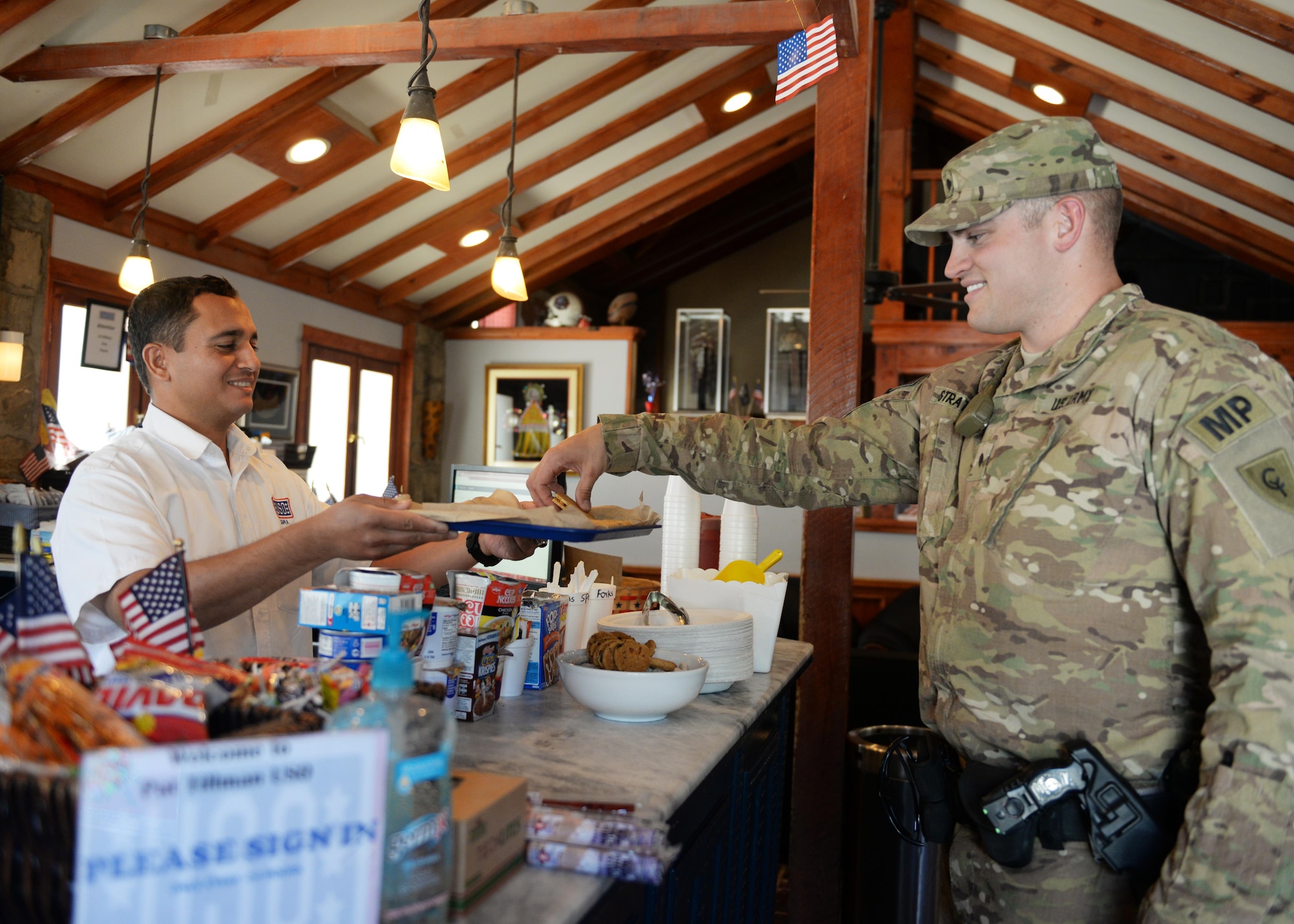 Sarhad Aziz, United Service Organization duty manager, gives a USO visitor snacks July 14, 2015, at the Pat Tillman Memorial Center, Bagram Airfield, Afghanistan. The Bagram USO is a facility for military members to go and relax in a comfortable environment as well as make free phone calls to loved ones.(U.S. Air Force photo by Senior Airman Cierra Presentado/Released)