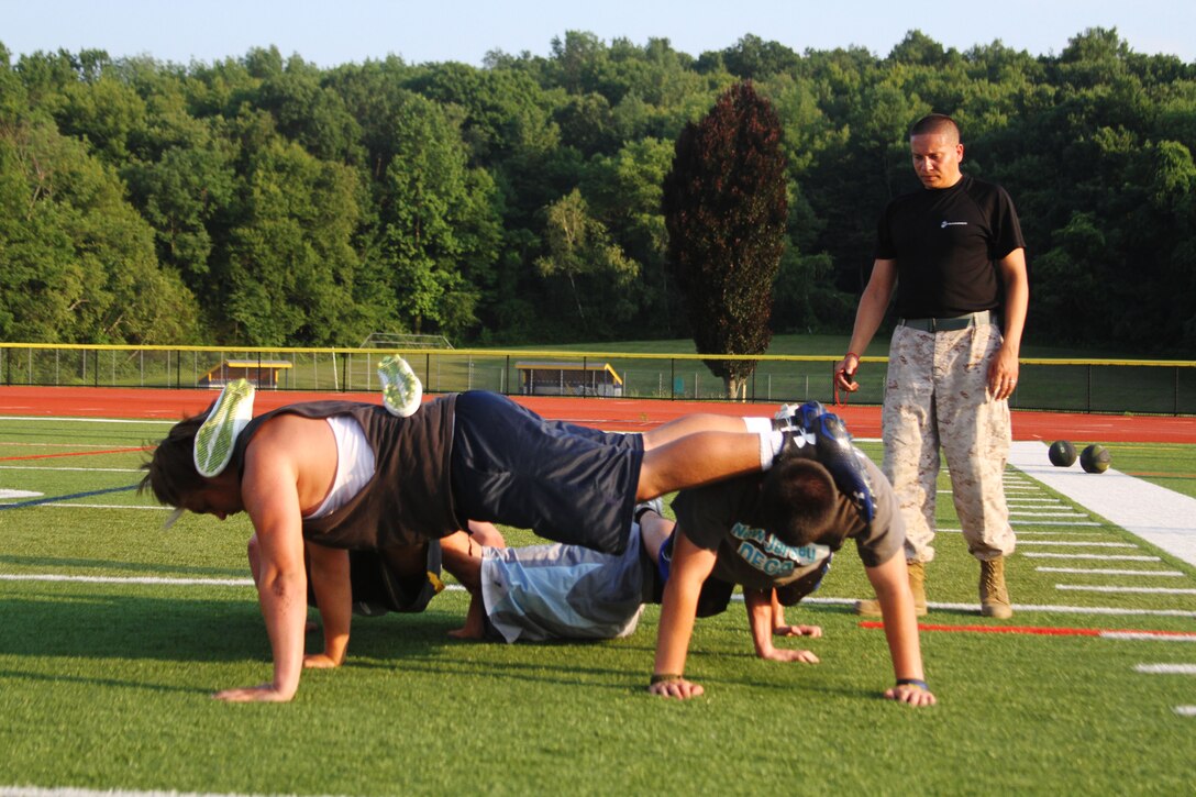 Staff Sgt. Alvaro Restrepo, canvassing recruiter with Recruiting Substation Northwest, supervises a fireteam conduct the four-man push-up station during a leadership seminar with the Vernon Township High School football team, July 13, 2015. 