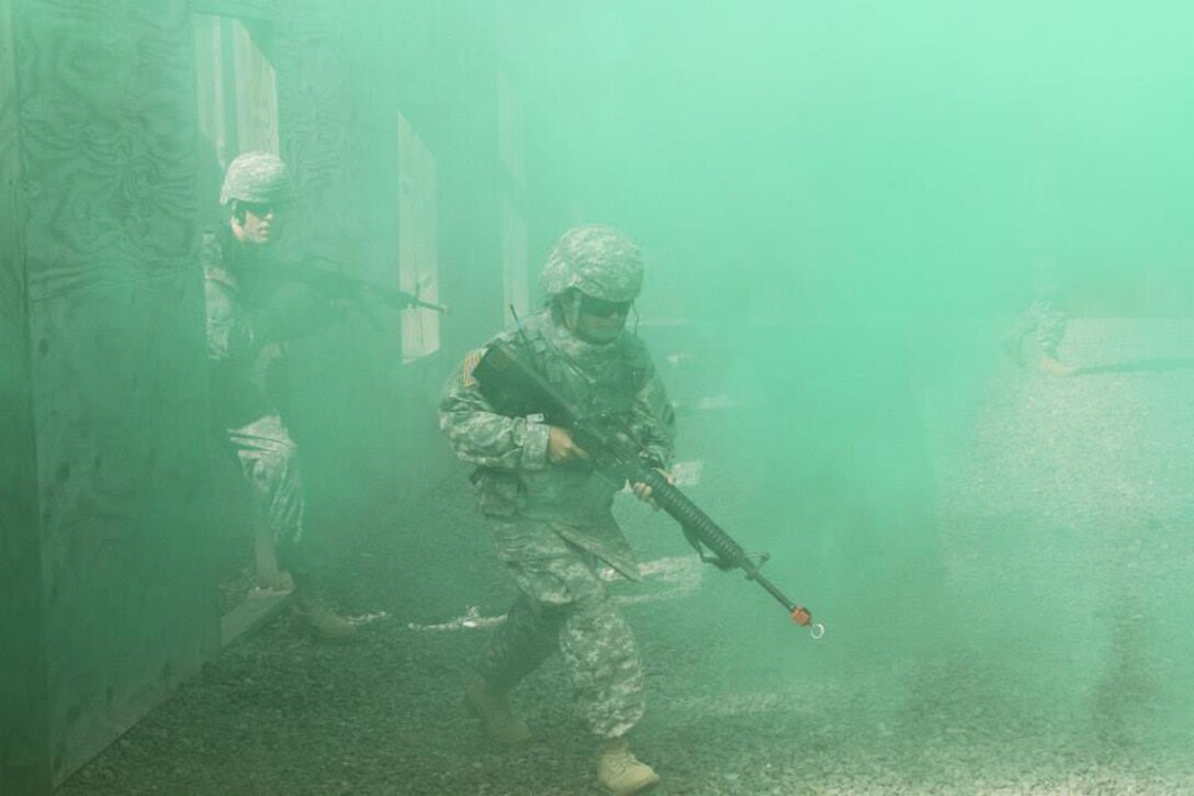 Sgt. 1st Class Maylene Ysasaga, automated logistical specialist with FORSCOM Augmentation Unit out of Fort Bragg, N.C., runs through the smoke with her squad after clearing a room at the Urban Warfare Site at Joint Base Mcguire-Dix-Lakehurst, April 22, 2014. The competitors of the Best Warrior Competition compete in multiple events over several days to determine the winner. (U.S. Army Photo by Staff Sgt. Kai L. Jensen)