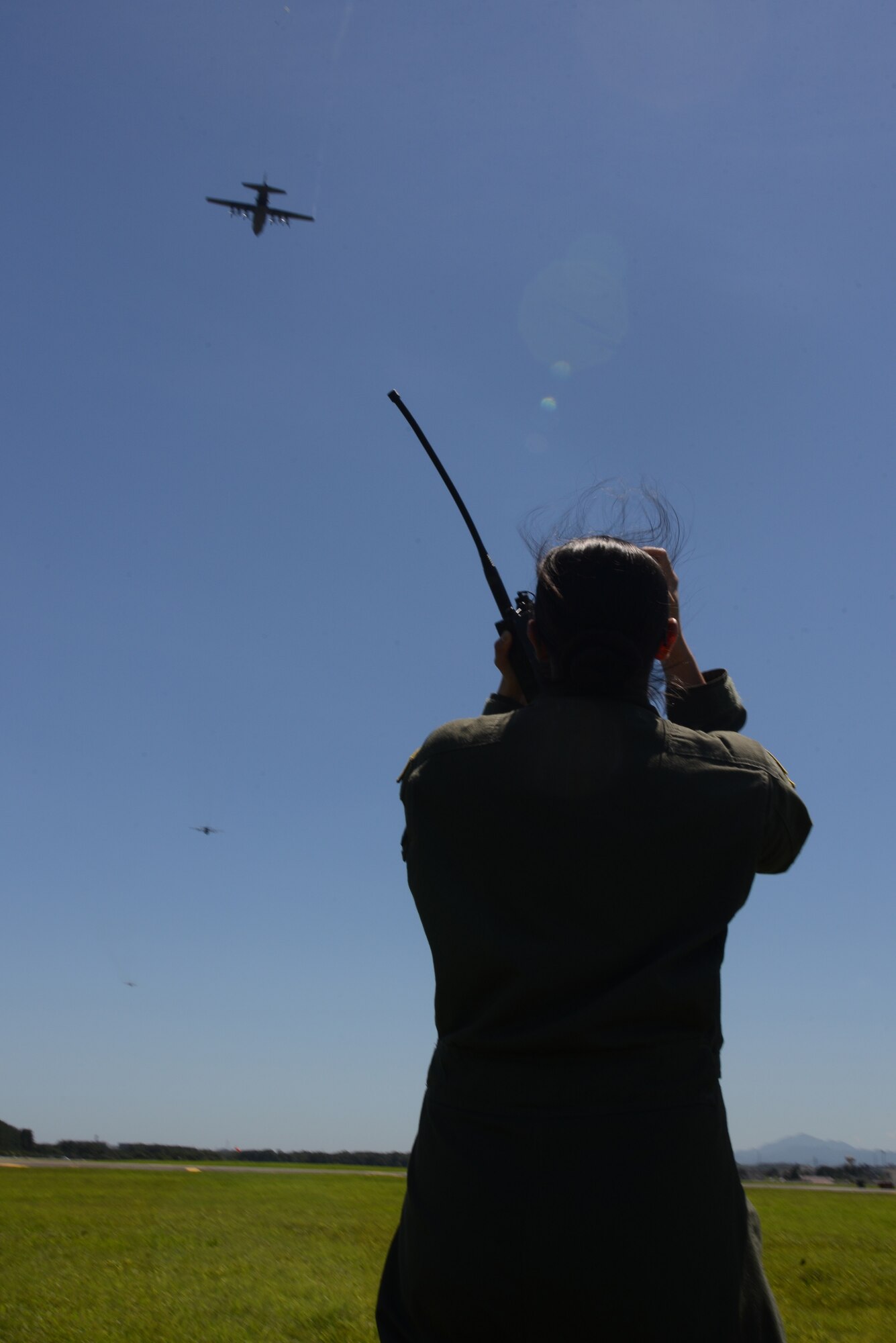 Airman 1st Class Marissa Antillon-Loya, 36th Airlift Squadron loadmaster, coordinates with a C-130 Hercules aircrew during a surge mission at Yokota Air Base, Japan, July 14, 2015. Nine C-130s took off during the surge, practicing their large formation and airlift capabilities. (U.S. Air Force photo by Airman 1st Class David C. Danford/Released)