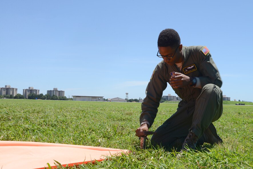 Airman 1st Class Deondre Rogers, 36th Airlift Squadron loadmaster, sets up a raised angle marker on a drop zone in Yokota Air Base, Japan, July 14, 2015. The RAM provides a visible target for C-130 Hercules aircrew to aim for when dropping bundles. (U.S. Air Force photo by Airman 1st Class David C. Danford/Released)