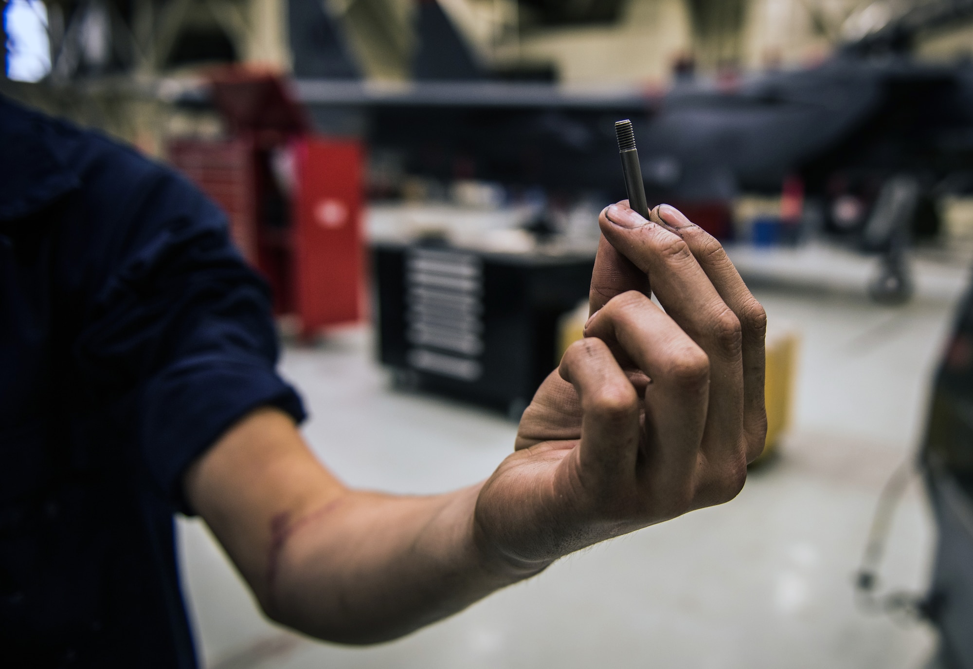 Airman 1st Class Saul Vasquez, 366th Equipment Maintenance Squadron phase inspection team member, holds an example of the bolt that tore his radial artery at Mountain Home Air Force Base, Idaho. The incident inspired new initiatives to supply trauma kits across the base. (U.S. Air Force photo by Airman 1st Class Connor J. Marth)