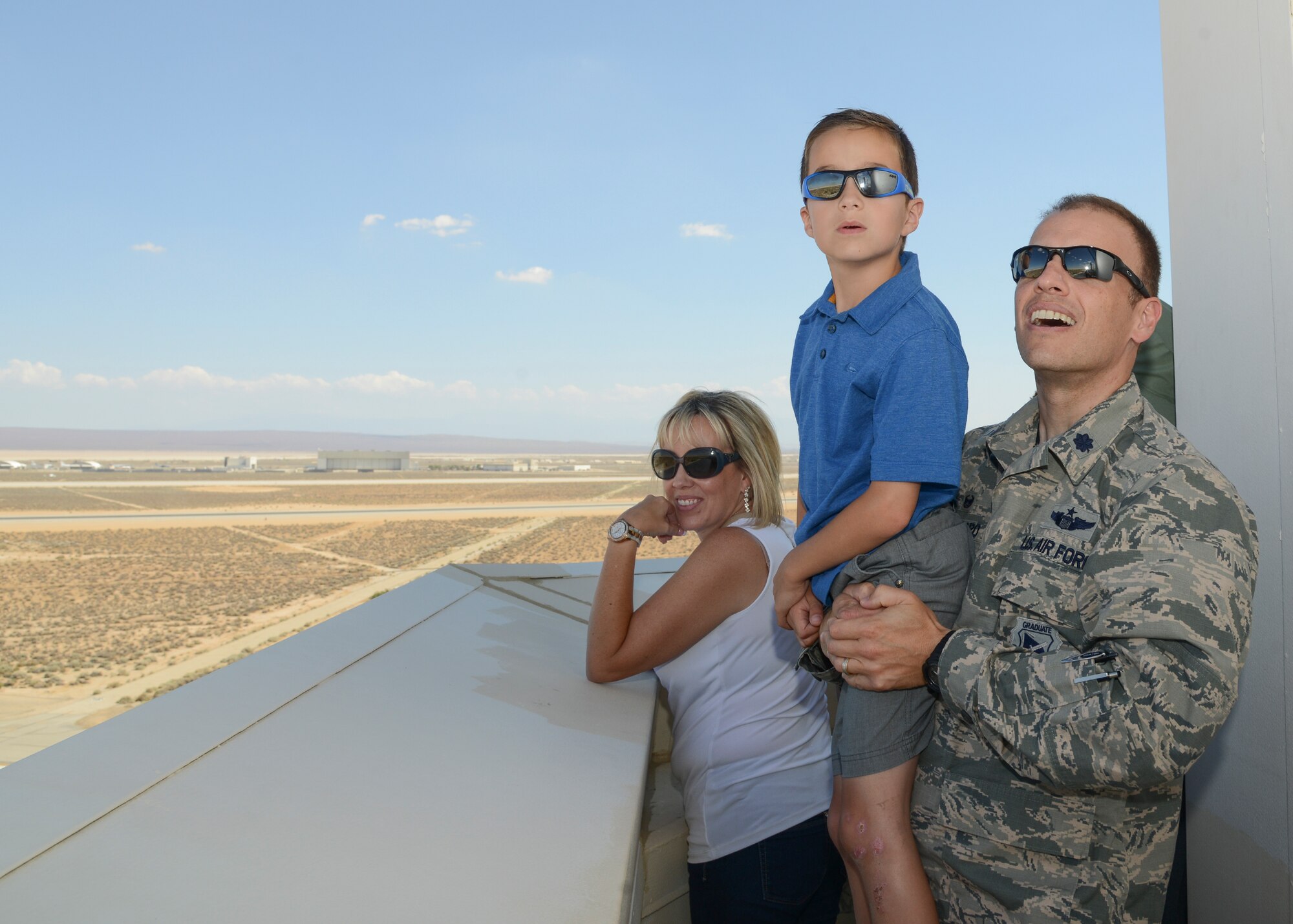 Lt. Col. Mark Massaro, 412th Operations Support Squadron commander, gives young Vincent a boost to watch a jet fly past the Edwards tower. Vincent attended the tour with his mother, honorary commander Ronda Perez (left). (U.S. Air Force photo by Rebecca Amber)