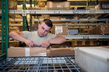 U.S. Air Force Airman 1st Class Cody Masterson, 23d Logistics Readiness Squadron material management apprentice, removes a label from a hydraulic water pump shipping box July 8, 2015, at Moody Air Force Base, Ga. Masterson removed non-pertinent information from the shipping box before shipping it to the base Traffic Management Office. (U.S. Air Force photo by Airman Greg Nash/Released)