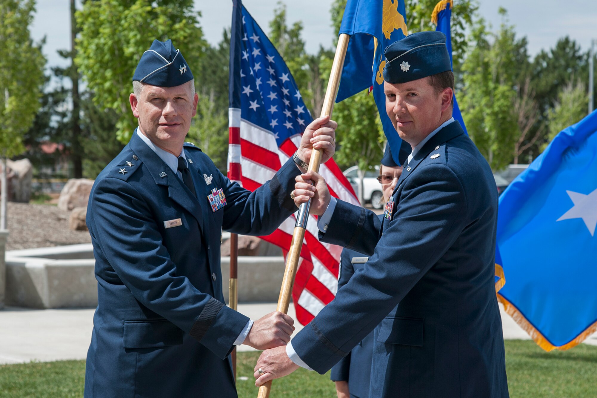 PETERSON AIR FORCE BASE, Colo. – Maj. Gen. Stephen Denker, director of Integrated Air, Space, Cyberspace and Intelligence, Surveillance and Reconnaissance Operations, Headquarters Air Force Space Command, passes the Advanced Space Operations School flag to Lt. Col. Matthew Bertsch who assumed command of the squadron July 13. Bertsch will lead a team providing career-long space system and deployment training for the National Security Space community and space orientation programs for all of the Department of Defense. These programs provide instruction on military space systems, space warfare concepts and employment of space tactics. (U.S. Air Force photo by Craig Denton)
