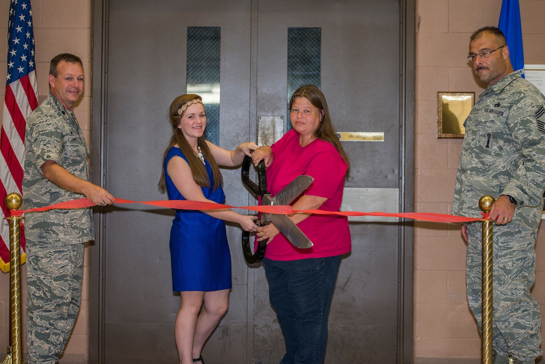 Lorie Whitt (center right) and her daughter, Ashley Whitt (center left), cut the opening ribbon for a room dedication to her father Kent “Doc” Salvage – Ashley’s grandfather – at the 363rd Training Squadron on Sheppard Air Force Base, Texas, July 14, 2015. Friends, colleagues and family attended the dedication ceremony to honor Salvage’s sacrifice to the U.S. Air Force. (U.S. Air Force photo by Senior Airman Kyle Gese/Released)