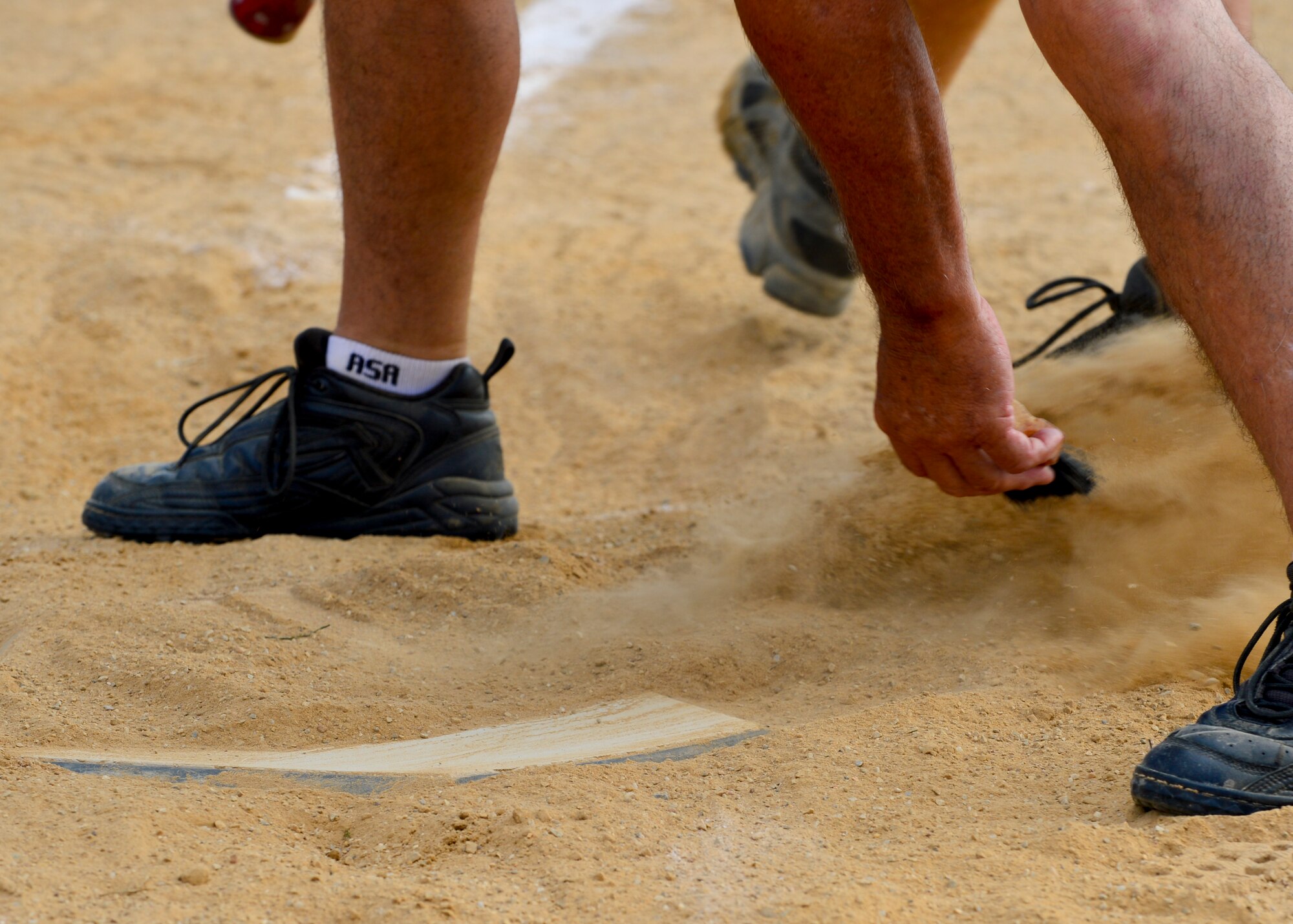 An umpire brushes off home plate after a player from the 436th Security Forces Squadron slid in for a run during an intramural softball game July 6, 2015, at the softball field on Dover Air Force Base, Del. The 436th SFS fell short against the 436th Aircraft Maintenance Squadron 18-12. (U.S. Air Force photo/Airman 1st Class William Johnson)