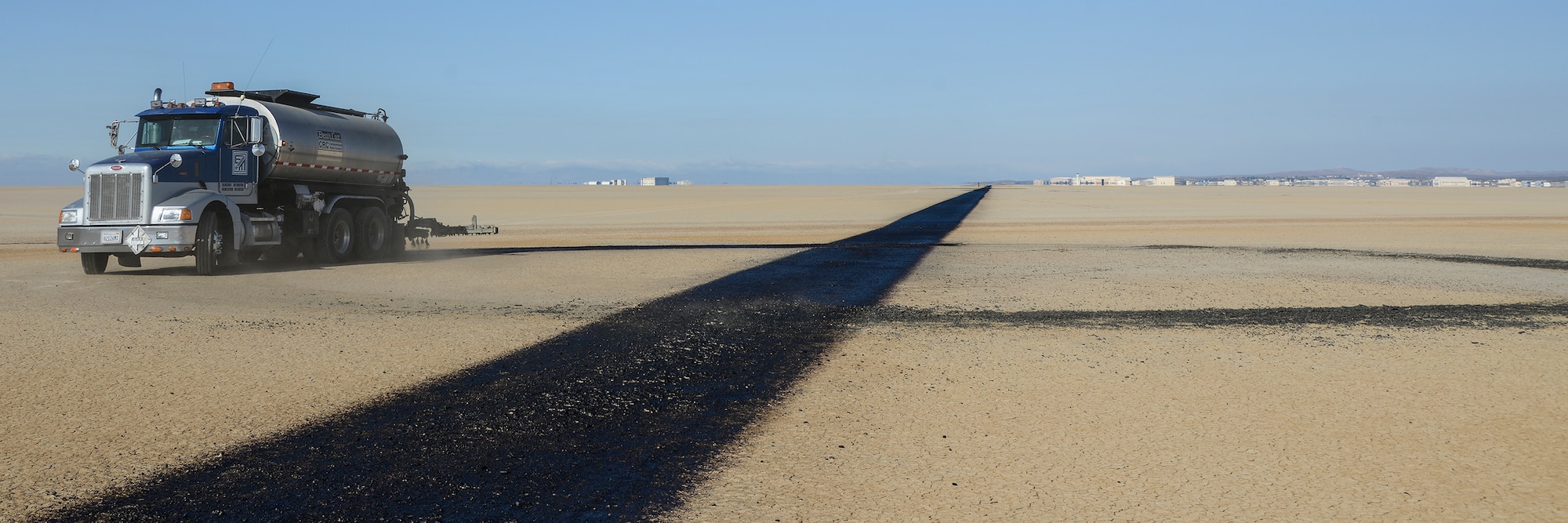 An oil spreader truck applies SSH1 to a quarter-mile marker along the fly-by line as part of the annual lakebed restriping process. (U.S. Air Force photo by Rebecca Amber)