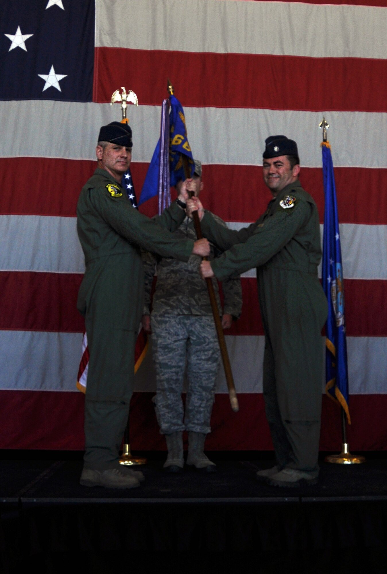 Col. Brian Silkey, 419th Operations Group commander, passes the 466th Fighter Squadron flag to Lt. Col. Surya Frickel during a change of command ceremony here this weekend. (U.S. Air Force photo/Staff Sgt. Crystal Charriere)