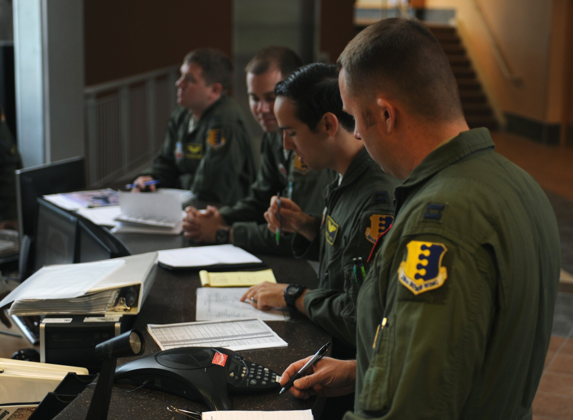 Pilots and weapons system operators from the 37th Bomb Squadron take notes during a step brief at Ellsworth Air Force Base, S.D., June 30, 2015. The pre-flight briefing informs pilots of weather patterns, airfield conditions, and jet status, enabling them to safely and accurately fly the B-1 bomber. (U.S. Air Force photo by Airman Sadie Colbert/Released)