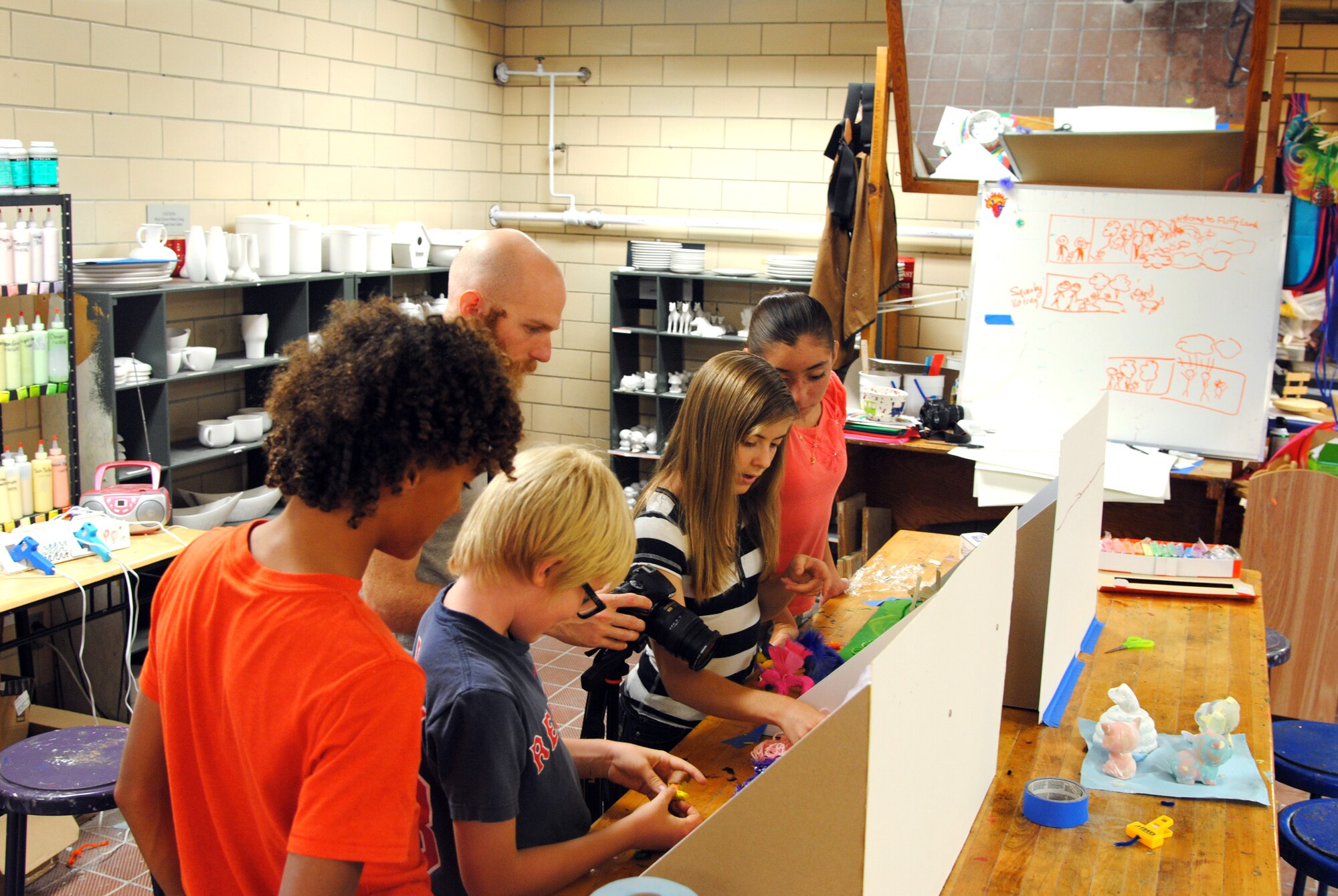 Youth at the Arts and Crafts Center work on a stop-motion clay animation film with the help of photographer Evan Curtis. The youth worked with clay to create characters and then took art supplies and random objects to create an elaborate backdrop that served as the set for filming. (Photo by Joanne Perkins)