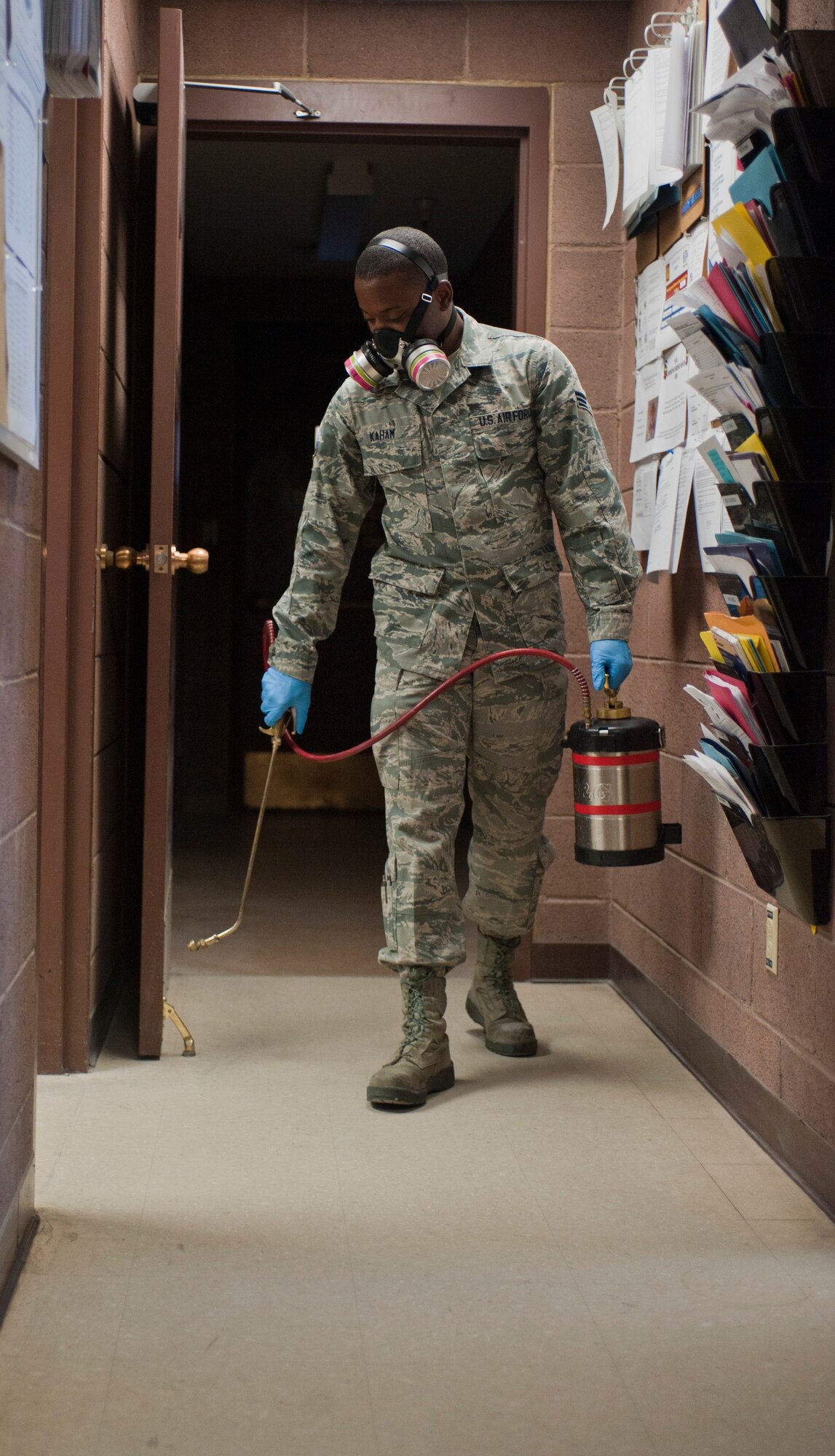 Senior Airman Stephen Kaham, 99th Civil Engineer Squadron pest management journeyman, sprays insecticide inside the pest management building on Nellis Air Force Base, Nev., June 29, 2015. Insecticide is used to exterminate and prevent ant and roach infestation around the base. (U.S. Air Force photo by Mikaley Towle)