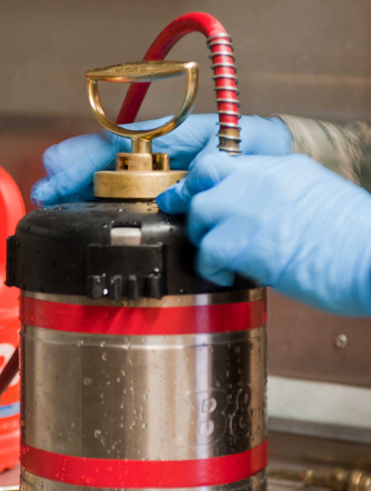 Senior Airman Stephen Kaham, 99th Civil Engineer Squadron pest management journeyman, cleans an insecticide container at the pest management shop on Nellis Air Force Base, Nev., June 29, 2015. Pest management sprays the inside and outside of buildings around base as needed. (U.S. Air Force photo by Mikaley Towle)