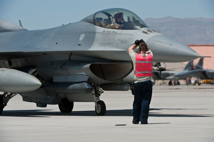 Staff Sgt. Nathaniel Hall, 55th Fighter Squadron dedicated crew chief, signals to a pilot during pre-flight checks before a Red Flag 15-3 sortie at Nellis Air Force Base, Nev., July 13, 2015. Red Flag is conducted on the Nevada Test and Training Range and involves U.S. and allied forces from all branches of service. (U.S. Air Force photo by Airman 1st Class Jake Carter)