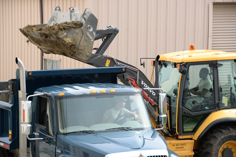 U.S. Air Force Airmen with the 181st Intelligence Wing Civil Engineering Squadron load piles of dirt from a construction site into a dump truck at Hulman Field, July 12, 2015. The squadron is in the beginning phases of building a running trail for the Airmen on base. (Air National Guard photo by Airman 1st Class Kevin D. Schulze/Released)