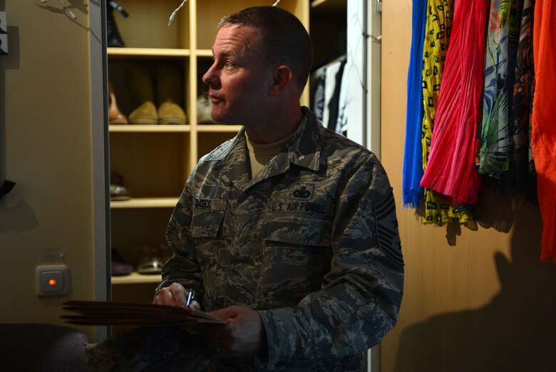 U.S. Air Force Chief Master Sgt. Brian Gates, 52nd Fighter Wing command chief, looks over a dorm room during the Dorm of the Quarter competition at Spangdahlem Air Base, Germany, July 8, 2015. In addition to judging the common areas of each dorm, inspectors also looked over two dorm rooms, one chosen by dorm residents and one randomly chosen during the inspection. (U.S. Air Force photo by 2nd Lt Meredith Mulvihill/Released)