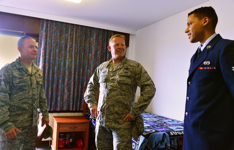 U.S. Airman First Class Ricardo Martin, 52nd Civil Engineering Squadron fire protection apprentice, shows off a dorm room to Col. Joe McFall, 52nd Fighter Wing commander, and Chief Master Sgt. Brian Gates, 52nd Fighter Wing command chief, during the Dorm of the Quarter inspections at Spangdahlem Air Base, Germany, July 8, 2015. Alongside the Dorm of the Quarter competition, one room in each dorm also competed for the title of Room of the Quarter. (U.S. Air Force photo by 2nd Lt Meredith Mulvihill/Released)