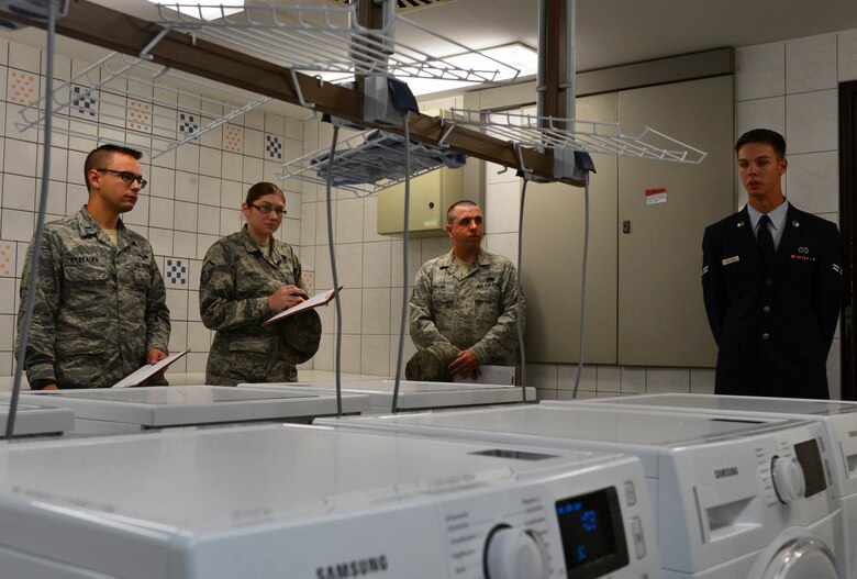 U.S. Air Force Airman First Class Charles Bratcher, 52nd Civil Engineering Squadron water and fuels system maintenance apprentice, tells inspectors about recent improvements to Dorm 225’s laundry facilities during the Dorm of the Quarter competition at Spangdahlem Air Base, Germany, July 8, 2015. Six dorms competed against one another to try and win the title of Dorm of the Quarter and accompanying prize of $1,000. (U.S. Air Force photo by 2nd Lt Meredith Mulvihill/Released)