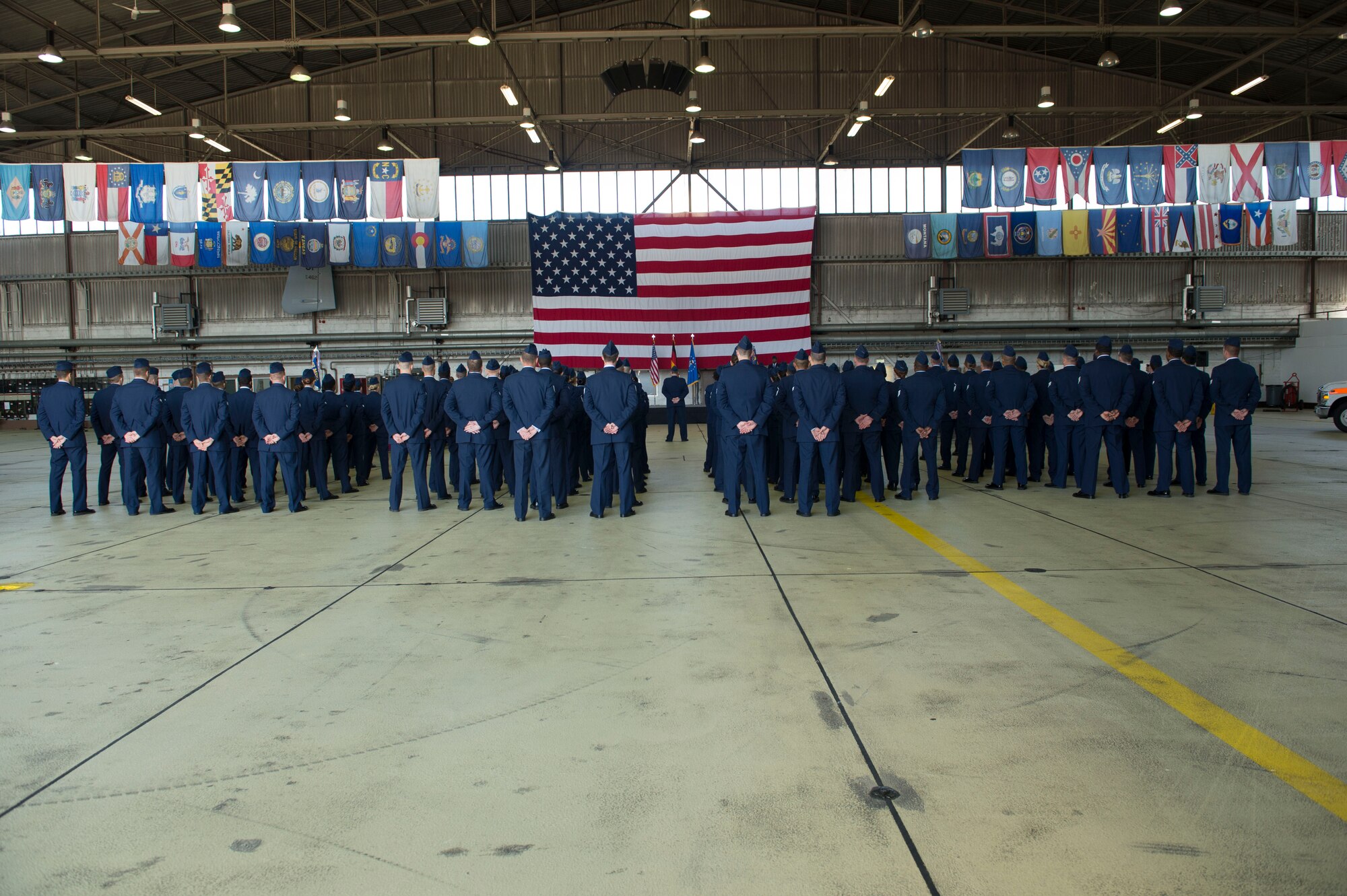 U.S. Air Force Airmen assigned to the 52nd Medical Group stand in formation during the 52nd MDG's change of command ceremony at Hangar One on Spangdahlem Air Base, Germany, July 10, 2015. The change of command is a military tradition that represents a formal transfer of authority and responsibility for a unit from one leader to another. (U.S. Air Force photo by Staff Sgt. Joe W. McFadden/Released)